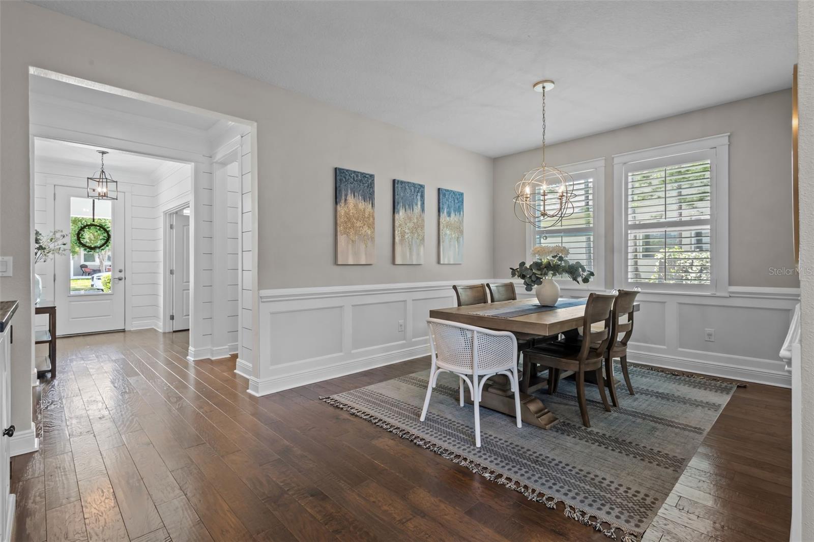 Formal dining space with wainscoting and a statement chandelier, seamlessly connected to the main living areas.