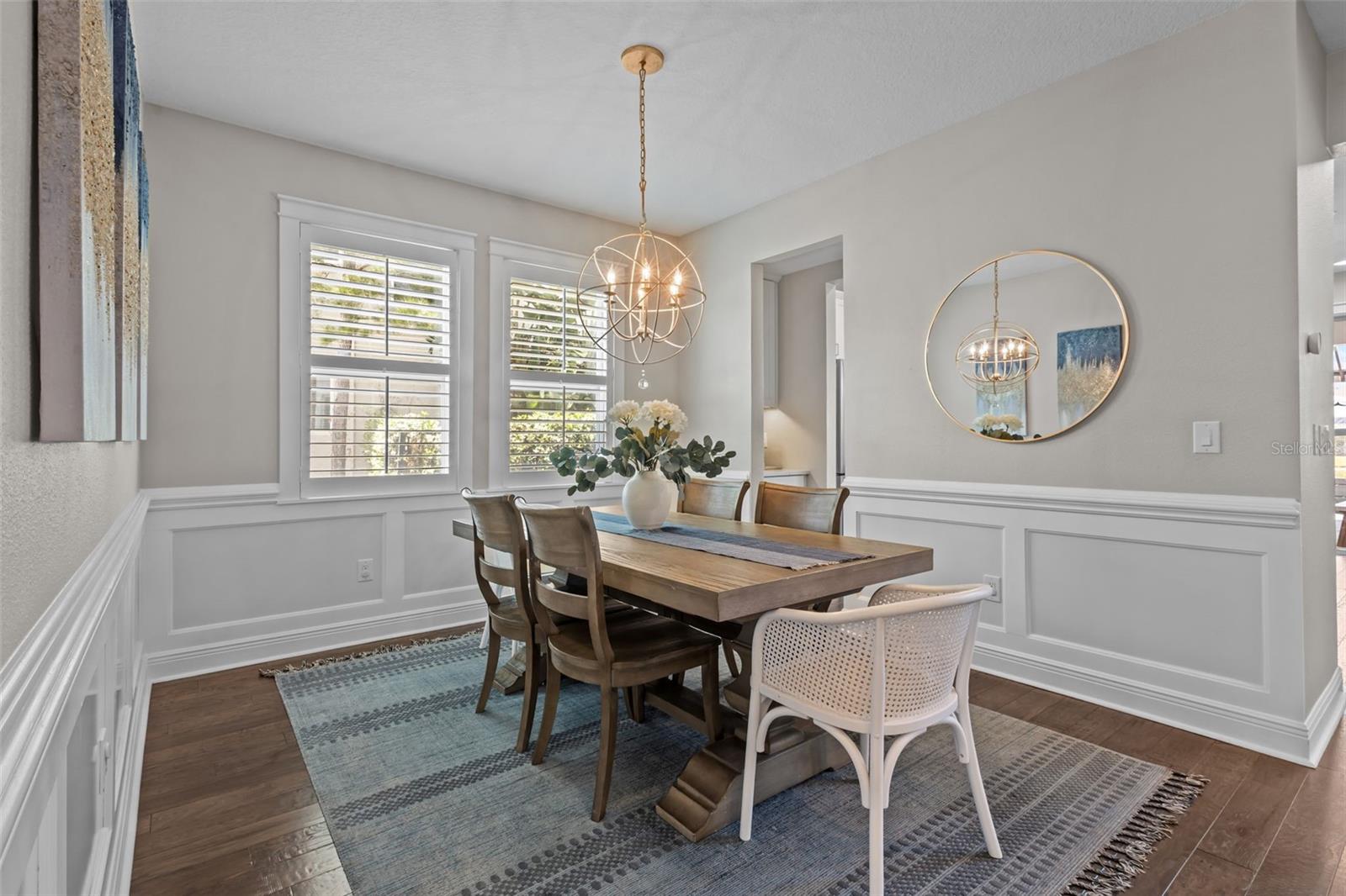 Formal dining space with wainscoting and a statement chandelier, seamlessly connected to the main living areas.