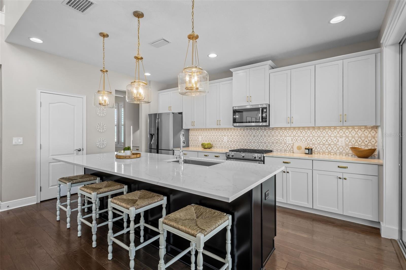 Updated in 2022 with quartz countertops, custom backsplash, gold hardware, pendant lighting, and under-cabinet lighting.