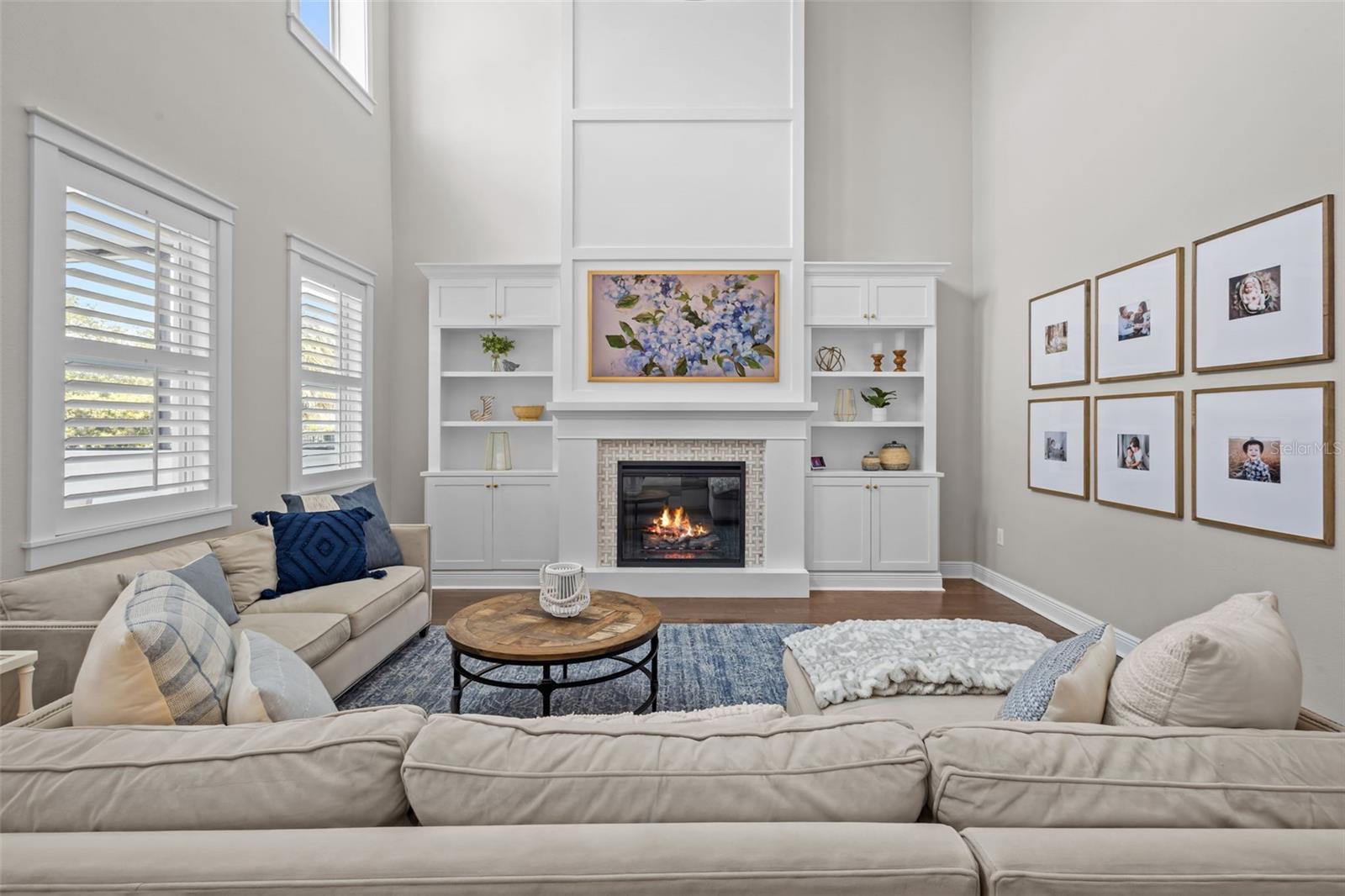 Two-story ceilings, a floor-to-ceiling fireplace, and built-in cabinetry create a bright, open focal point.