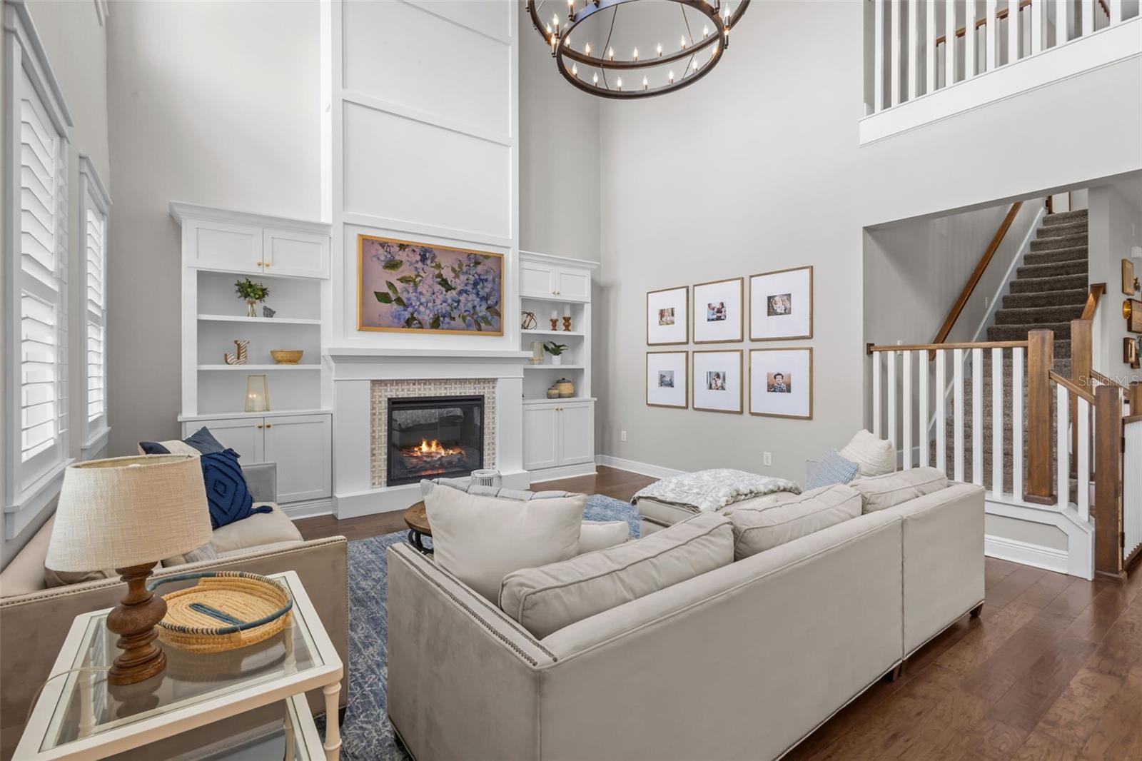 Two-story ceilings, a floor-to-ceiling fireplace, and built-in cabinetry create a bright, open focal point.