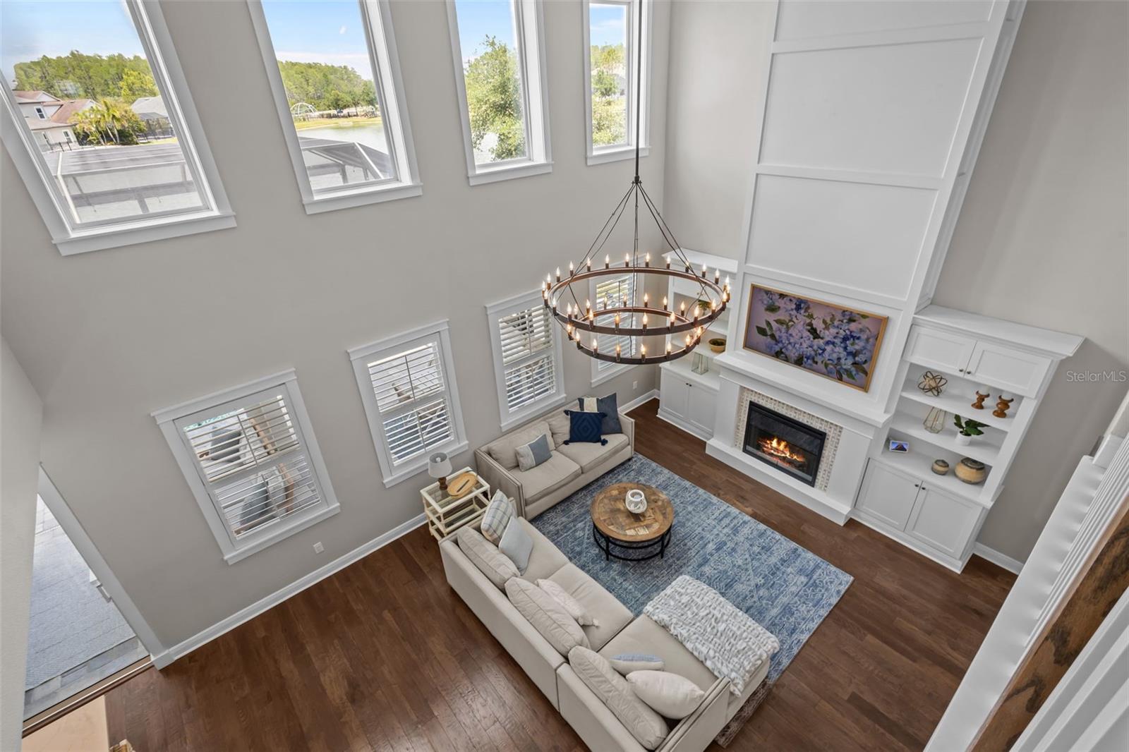 Two-story ceilings, a floor-to-ceiling fireplace, and built-in cabinetry create a bright, open focal point.