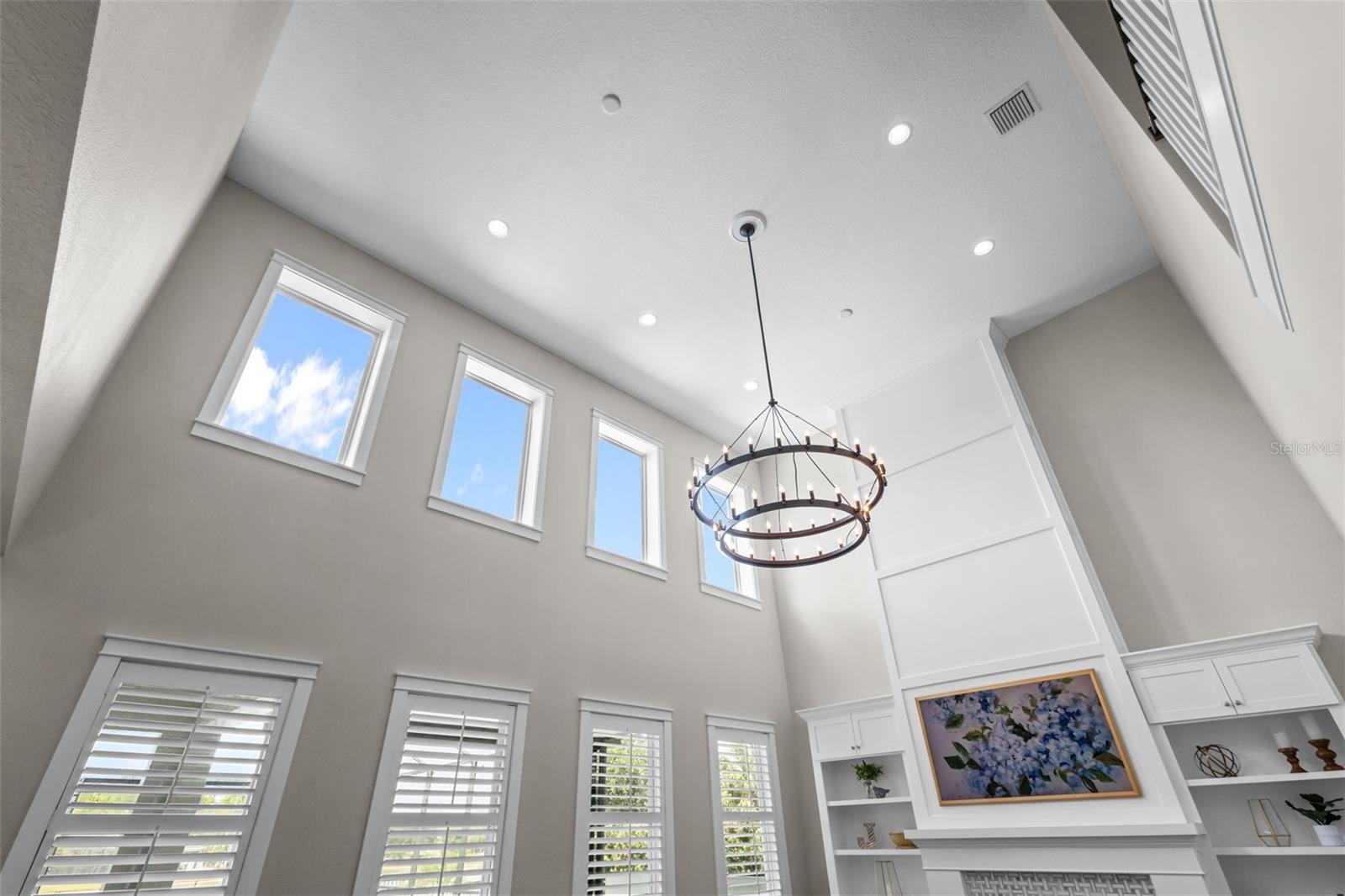 Two-story ceilings, a floor-to-ceiling fireplace, and built-in cabinetry create a bright, open focal point.