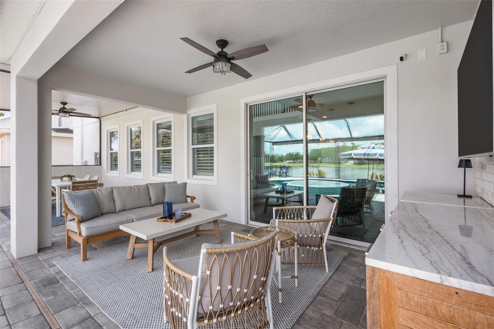 Screened lanai with covered seating area, brick accent wall, and space for dining and entertaining.
