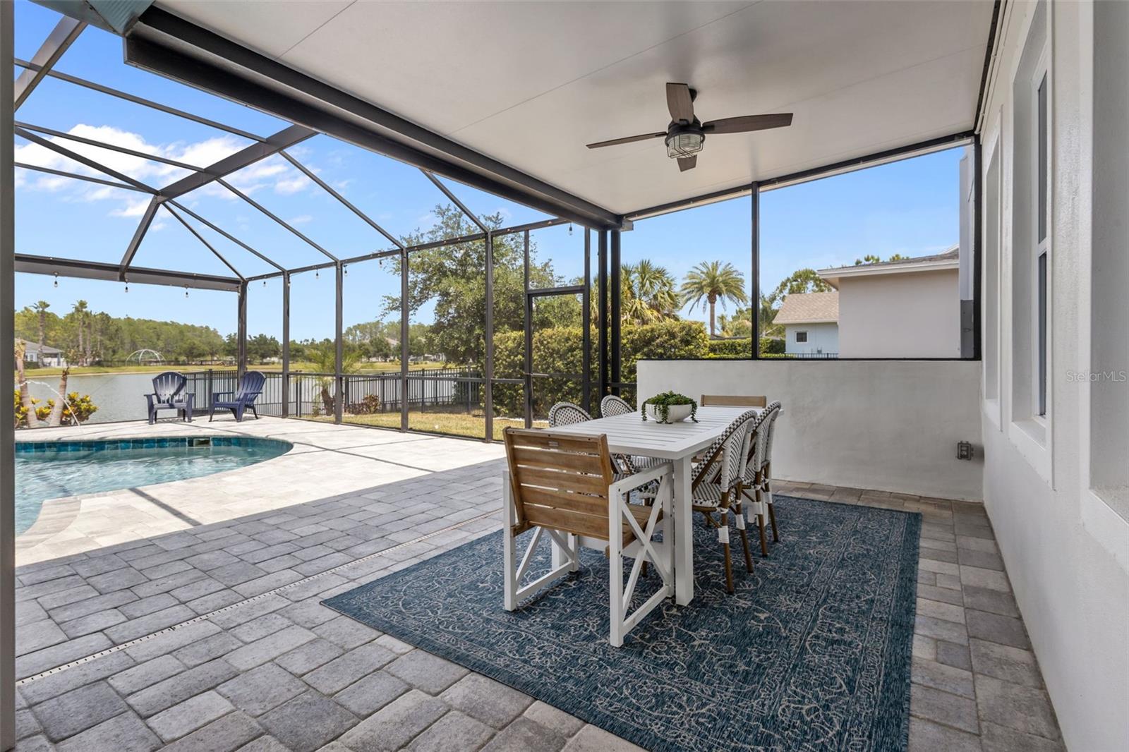 Screened lanai with covered seating area, brick accent wall, and space for dining and entertaining.