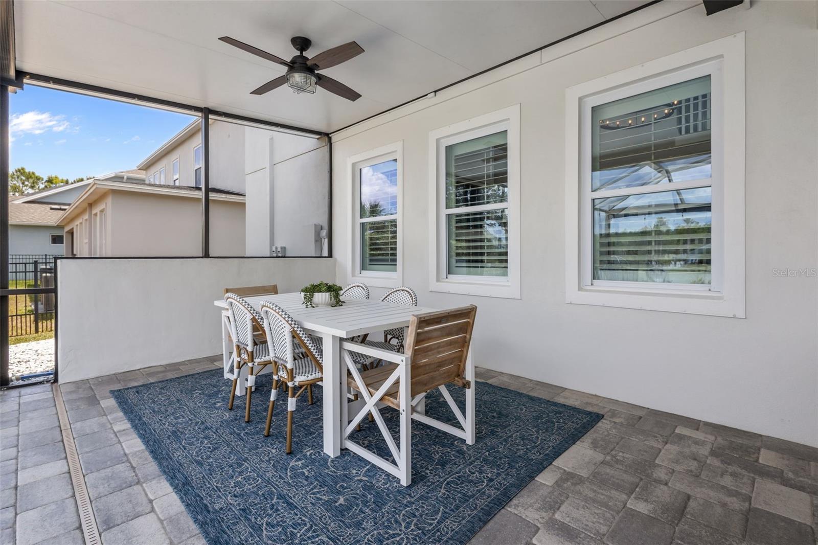 Screened lanai with covered seating area, brick accent wall, and space for dining and entertaining.