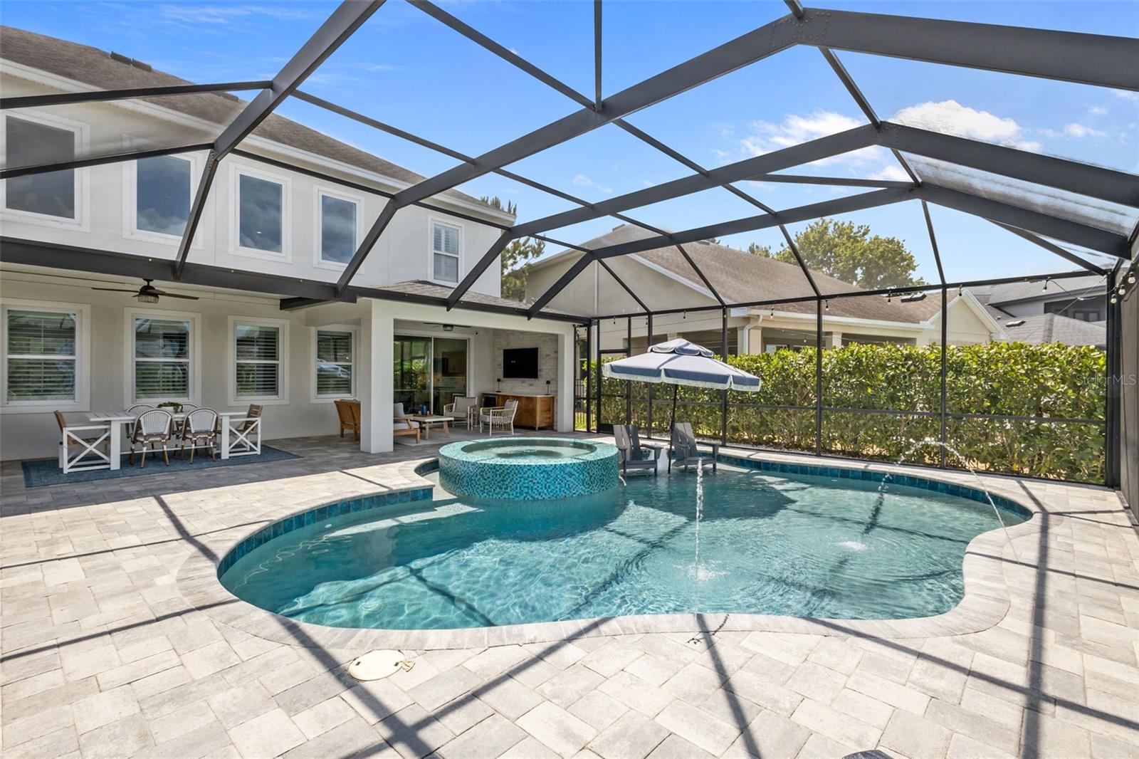 Gas-heated pool with infinity-edge spa, sunshelf, and water features, all overlooking a tranquil pond. Fenced side yard with tropical landscaping.