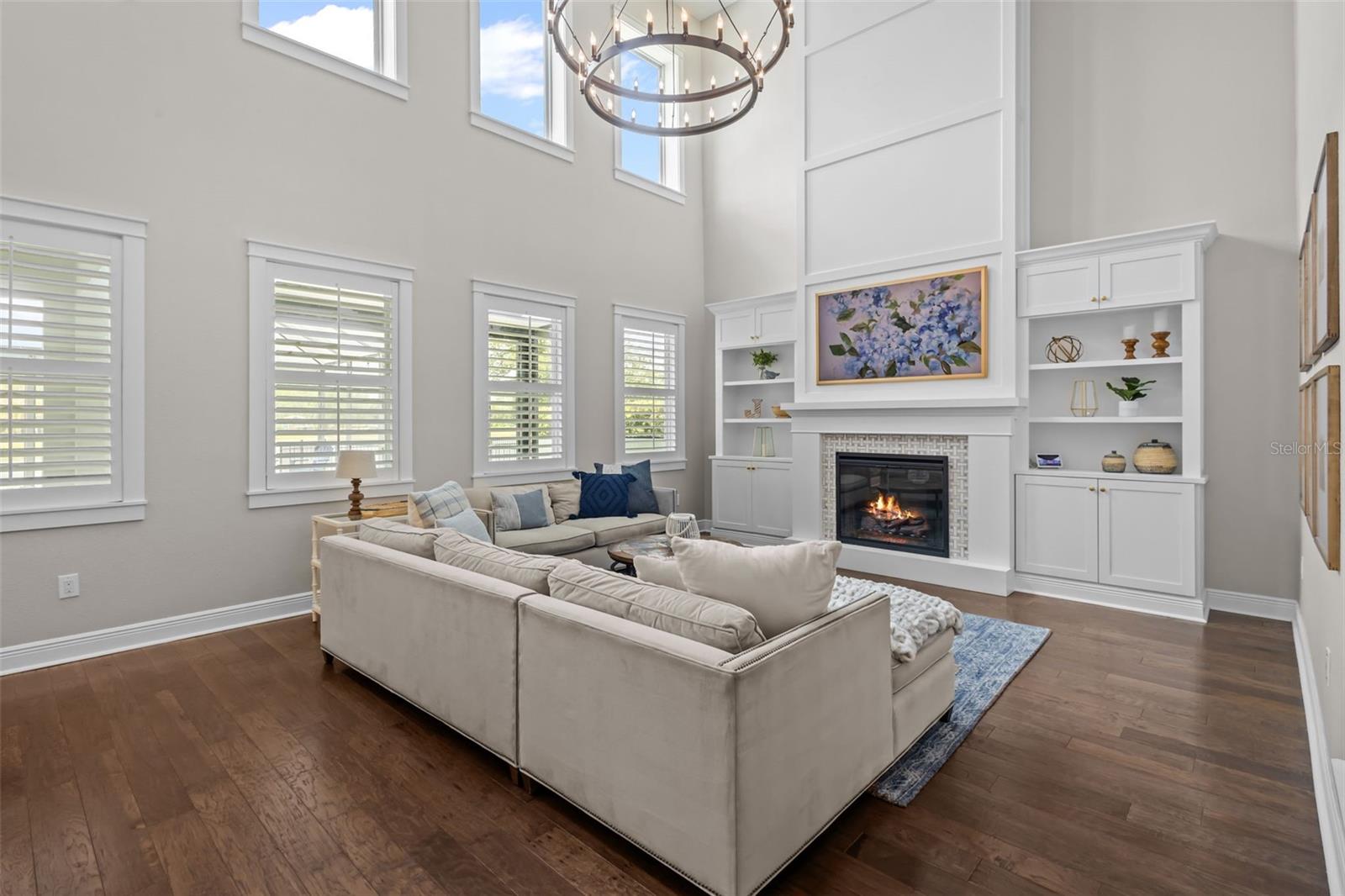 Two-story ceilings, a floor-to-ceiling fireplace, and built-in cabinetry create a bright, open focal point.