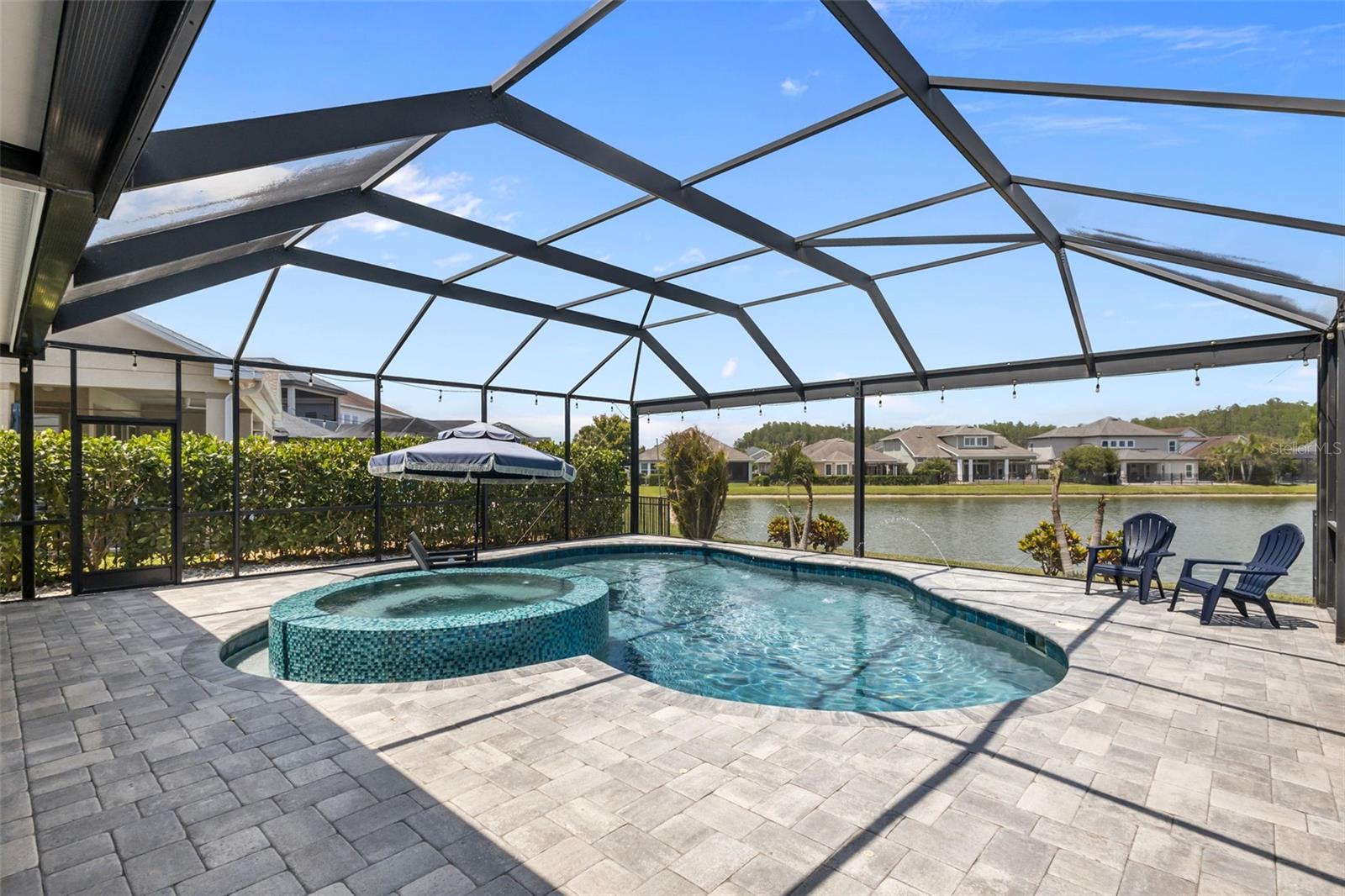 Gas-heated pool with infinity-edge spa, sunshelf, and water features, all overlooking a tranquil pond. Fenced side yard with tropical landscaping.
