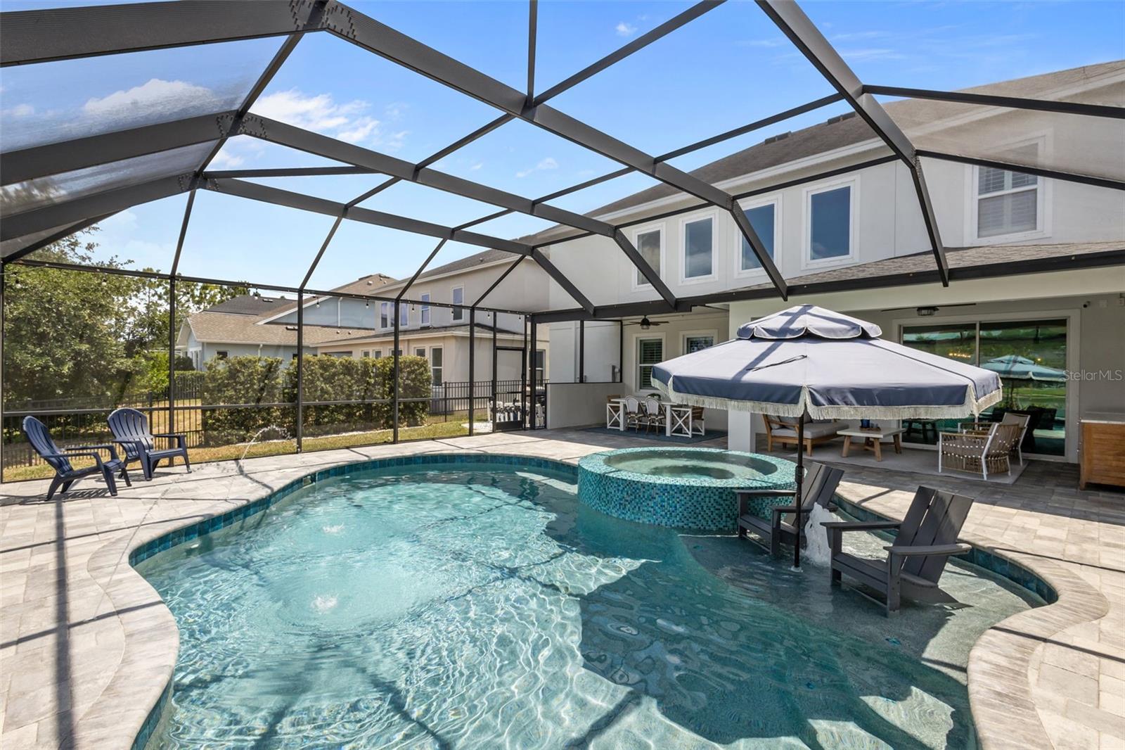 Gas-heated pool with infinity-edge spa, sunshelf, and water features, all overlooking a tranquil pond. Fenced side yard with tropical landscaping.