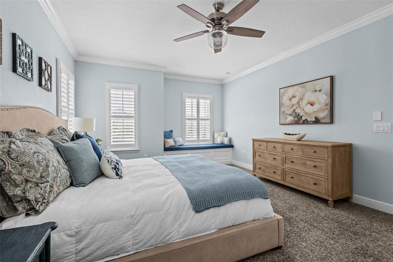 Spacious upstairs retreat with crown molding, natural light, and a built-in window seat with storage.