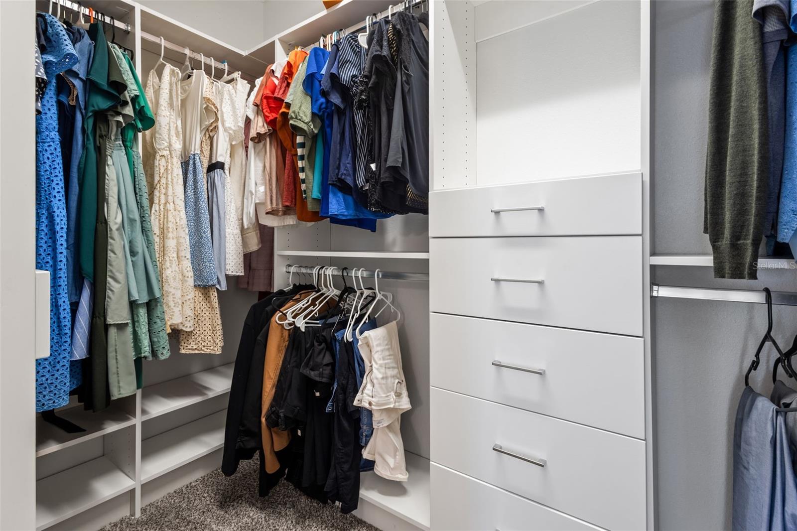 Primary bedroom walk in closet with custom built ins