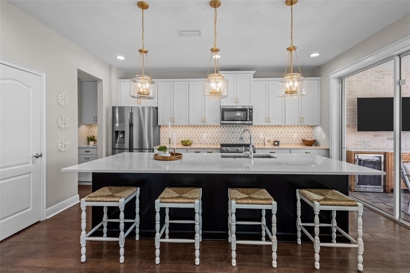 Updated in 2022 with quartz countertops, custom backsplash, gold hardware, pendant lighting, and under-cabinet lighting.