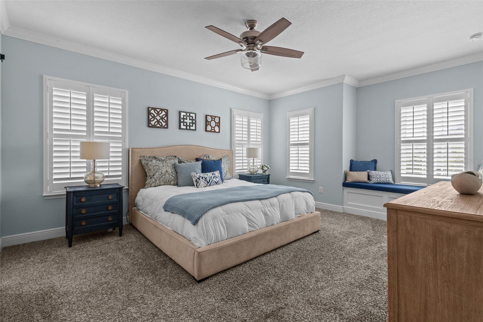 Spacious upstairs retreat with crown molding, natural light, and a built-in window seat with storage.
