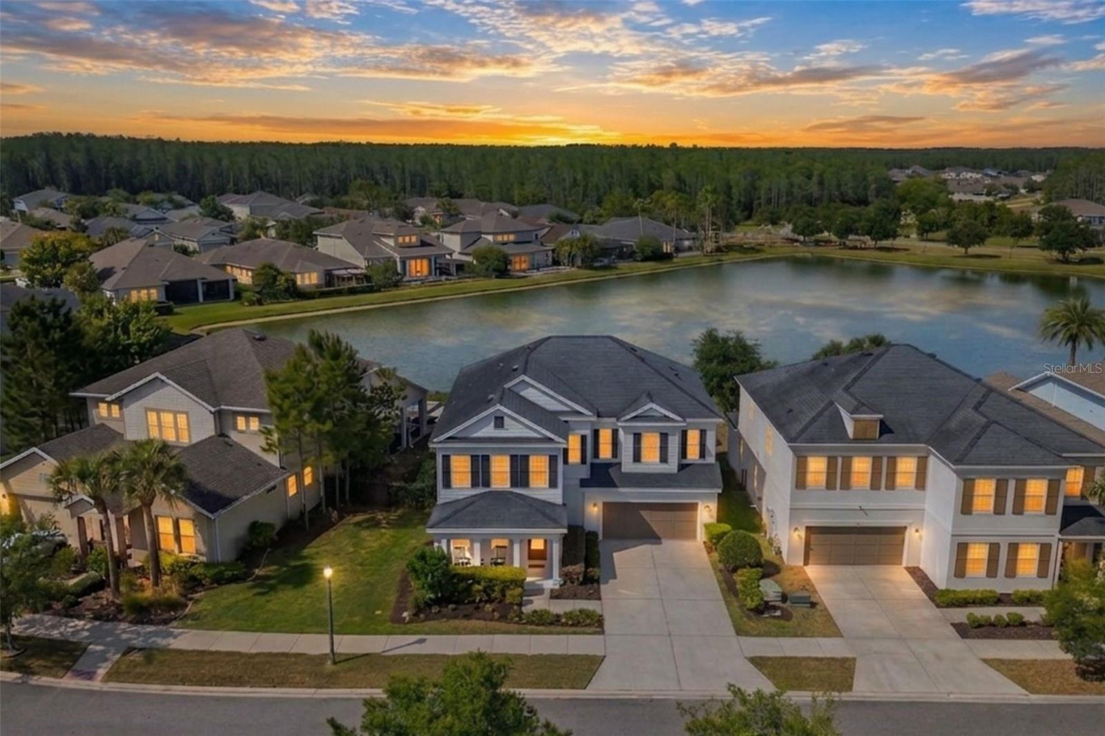 Pond-front home in Asturia with a screened lanai, gas-heated pool, and infinity-edge spa. Classic white exterior with black shutters, thoughtfully upgraded interior finishes, and a layout designed for both everyday living and entertaining