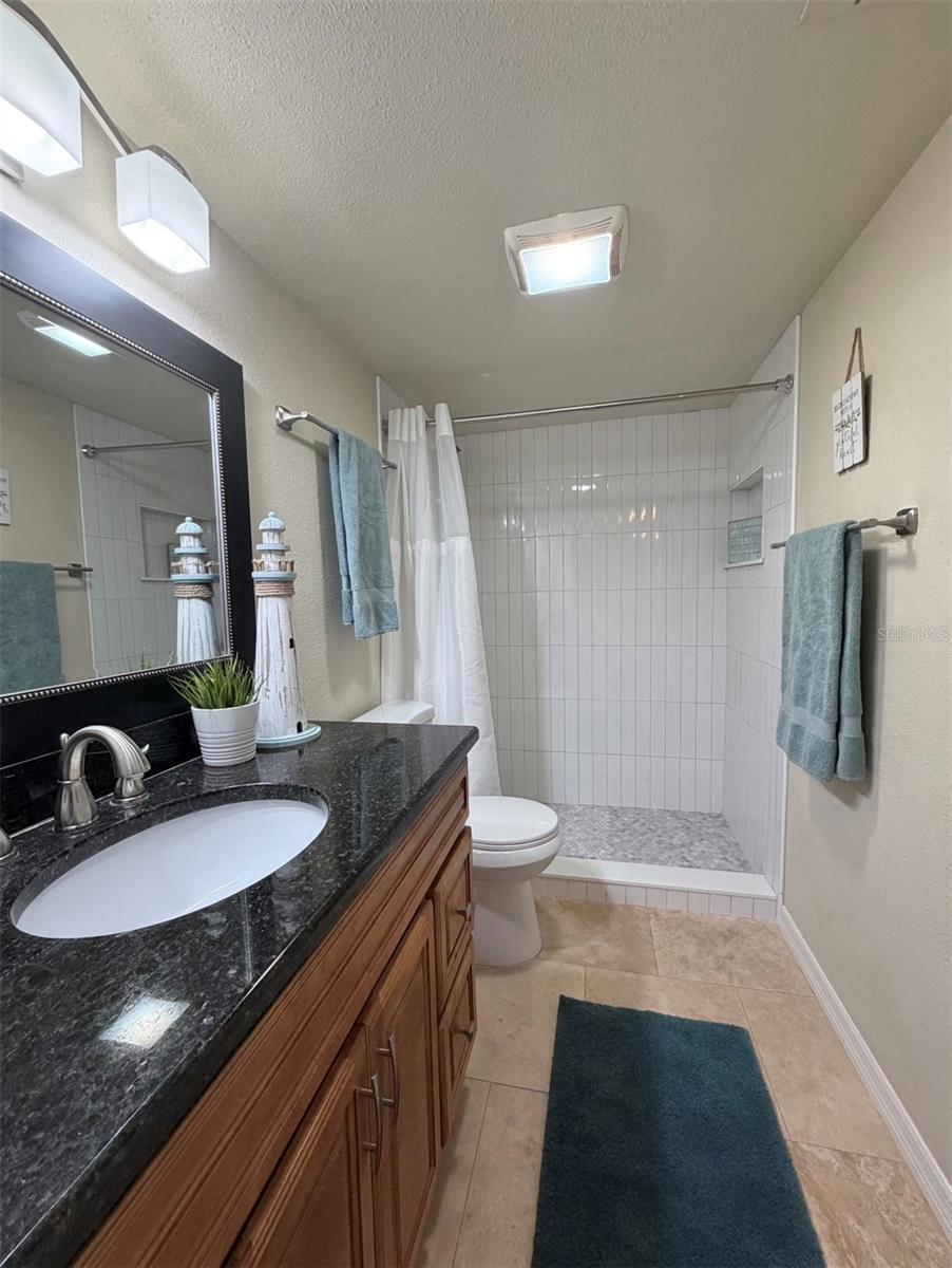 The primary ensuite features solid wood cabinets, granite counters, updated lighting, and a newly remodeled walk-in shower.