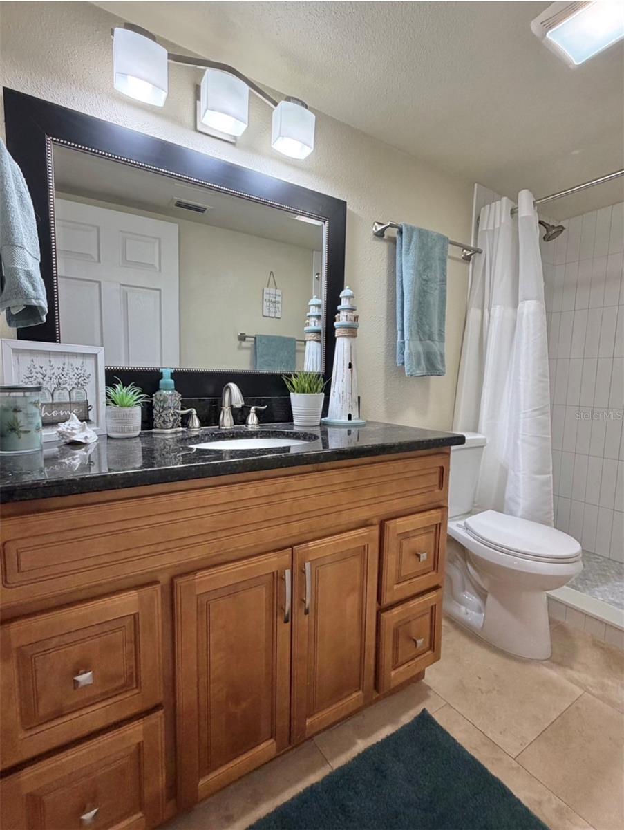The primary ensuite features solid wood cabinets, granite counters, updated lighting, and a newly remodeled walk-in shower.