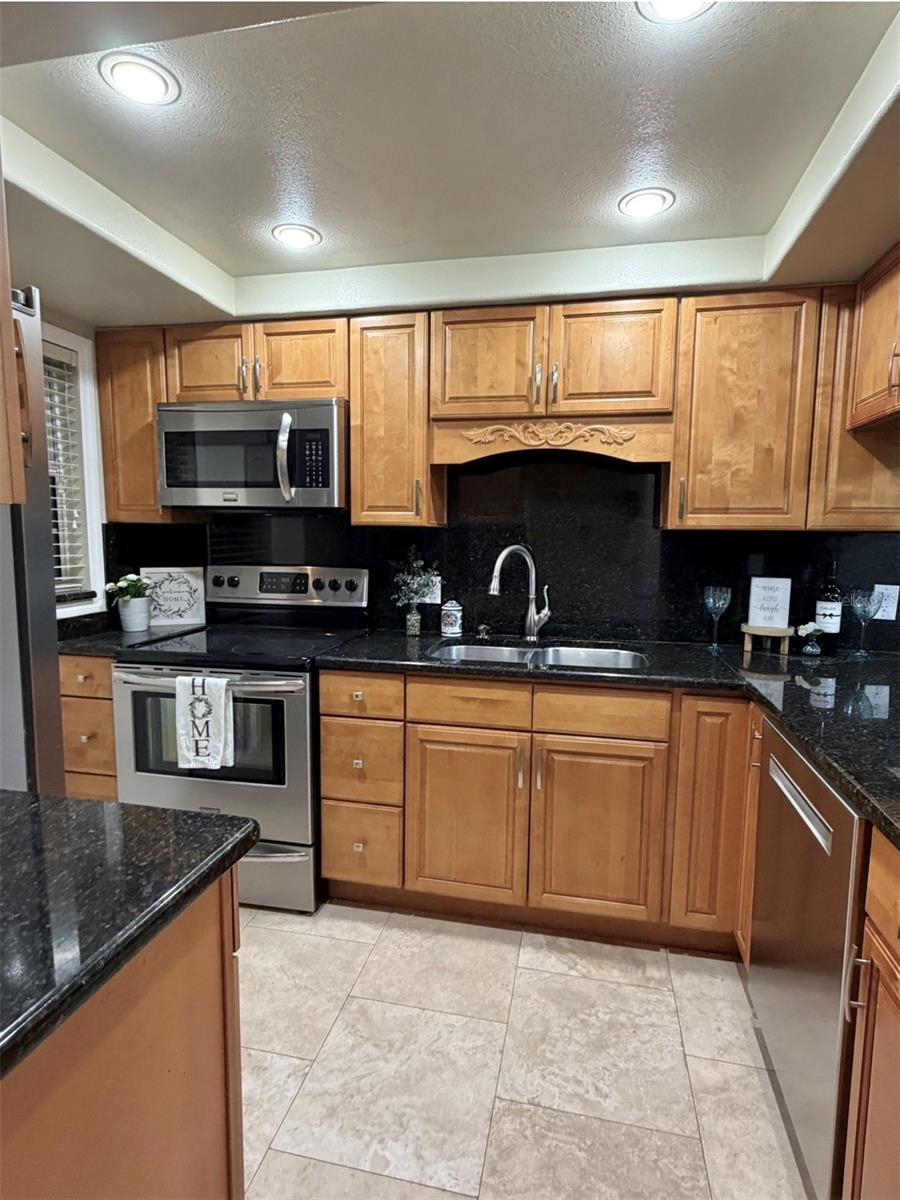 The Kitchen features solid wood cabinets, granite counters, updated lighting, stainless appliances, and an updated sink and faucet.