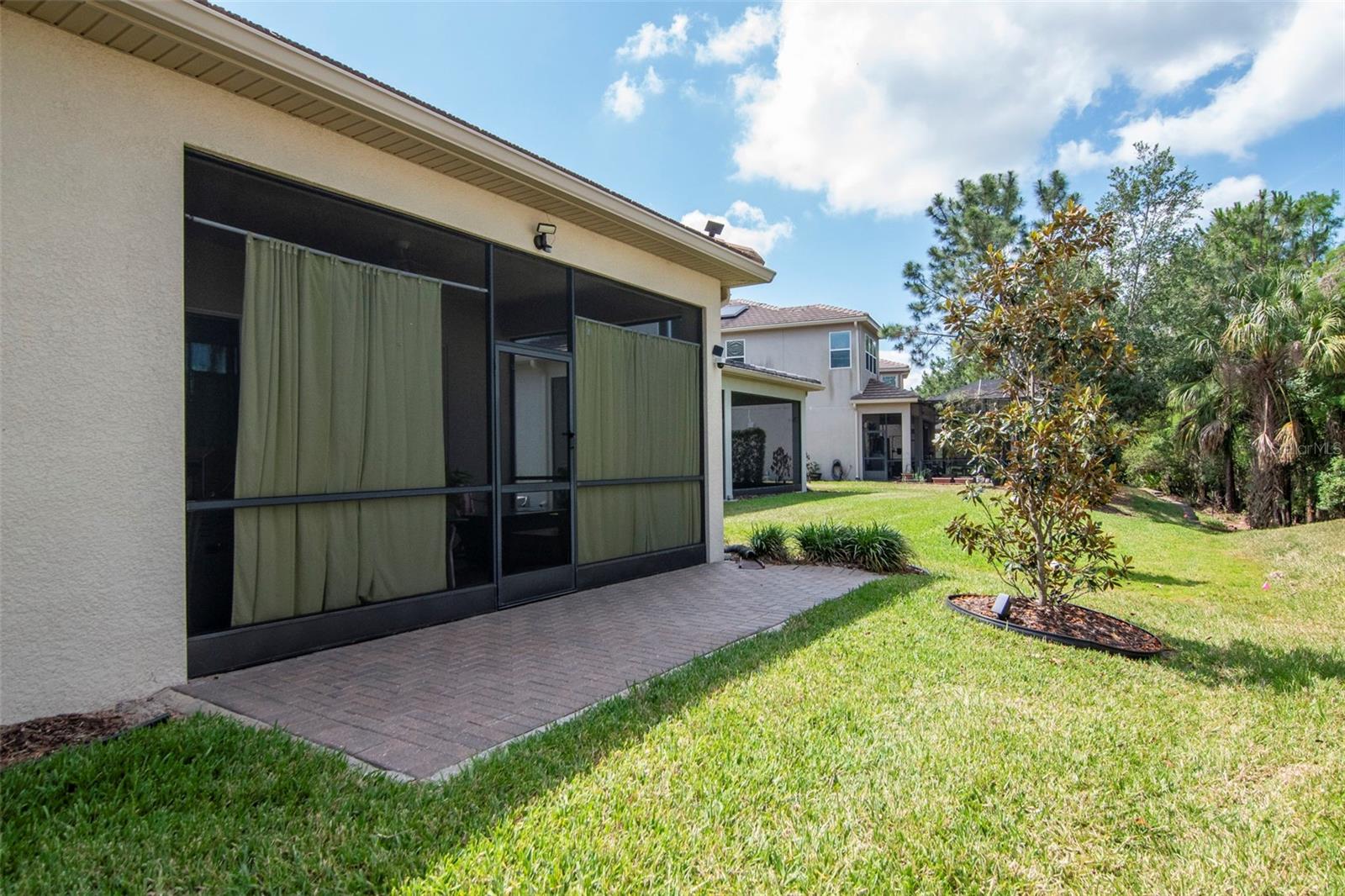 Back exterior featuring lanai and extended paver patio