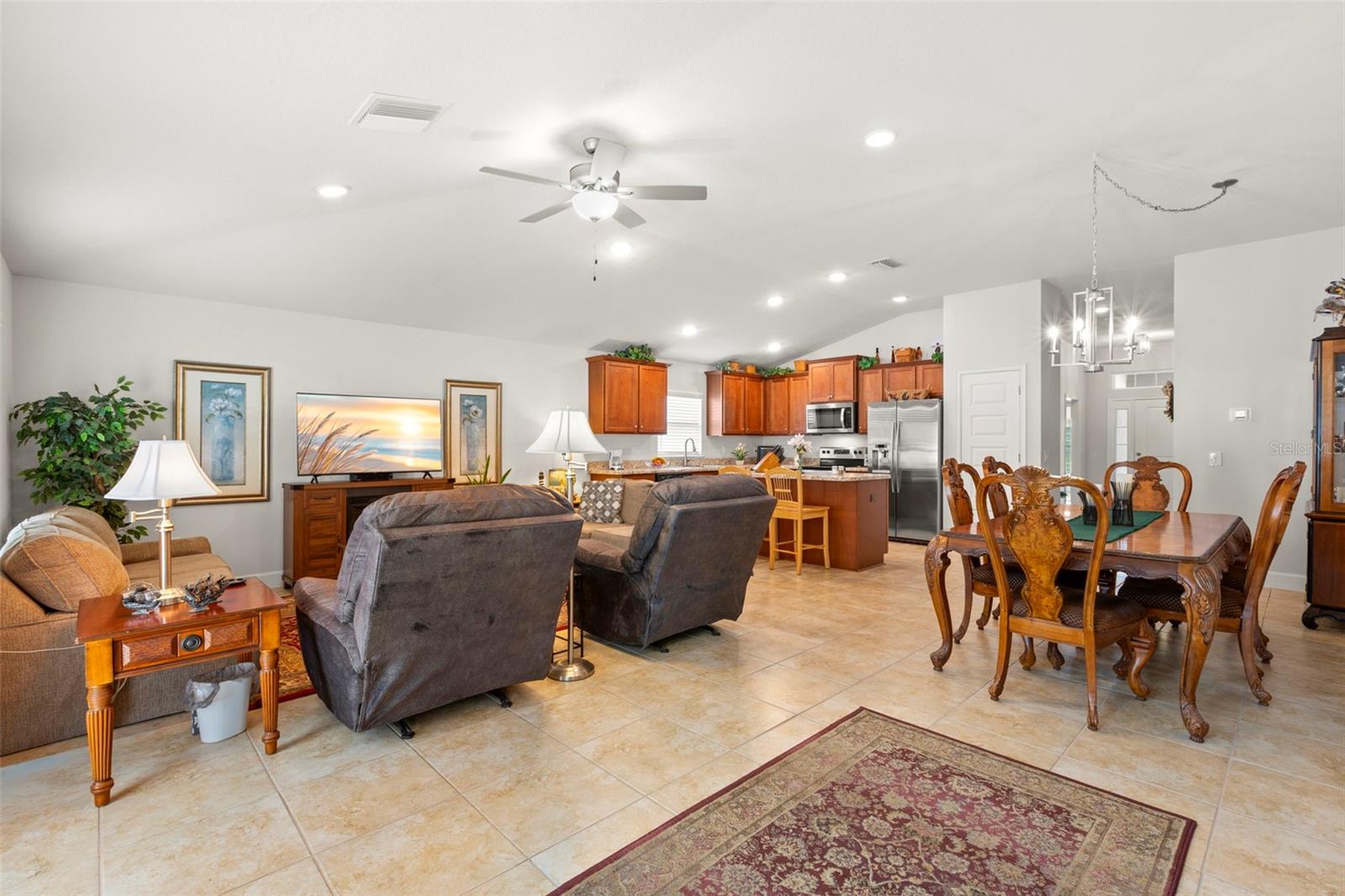 The expansive open-concept living and dining area flows seamlessly into the kitchen, highlighted by elevated ceiling height, oversized tile flooring, and an airy layout designed for comfortable daily living and effortless entertaining.