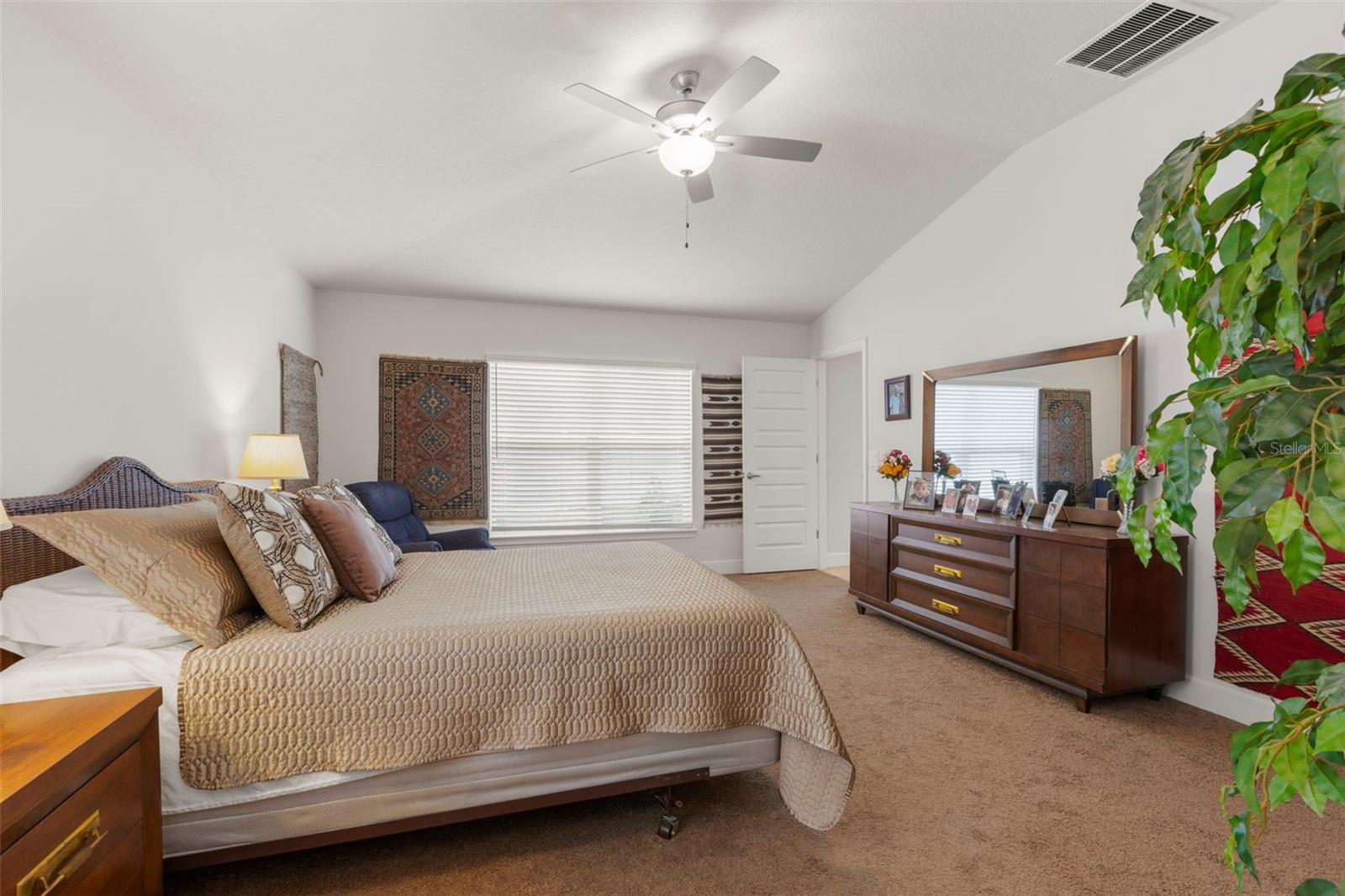 Designed for privacy, the spacious primary suite offers vaulted ceilings, a ceiling fan, neutral finishes, a walk-in closet, and direct access to the ensuite bath.