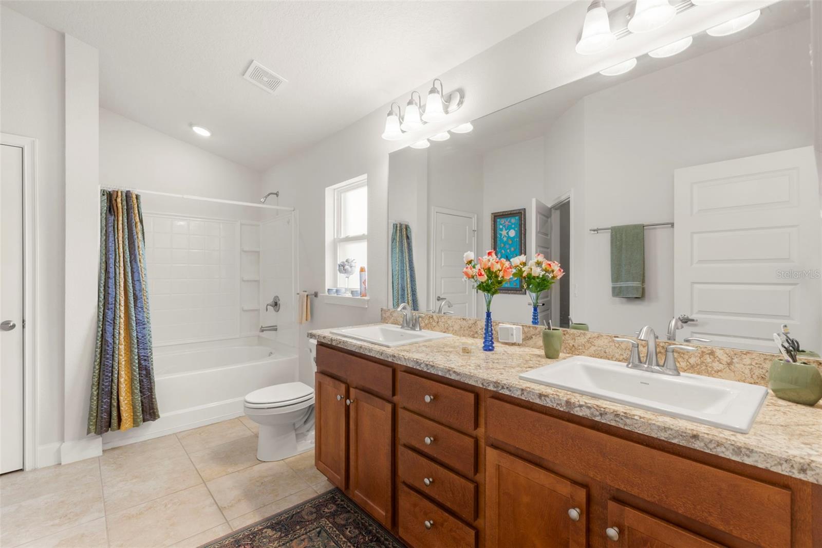 The ensuite bath includes dual vanities, a spacious tub/shower combination, and a privacy window that fills the space with natural light.