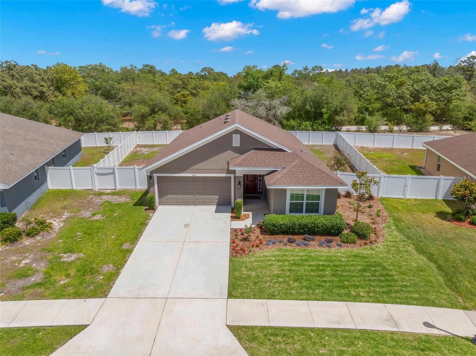 Bird’s-eye aerial view showcases the home’s premium lot placement, expansive fenced yard, and private wooded backdrop.