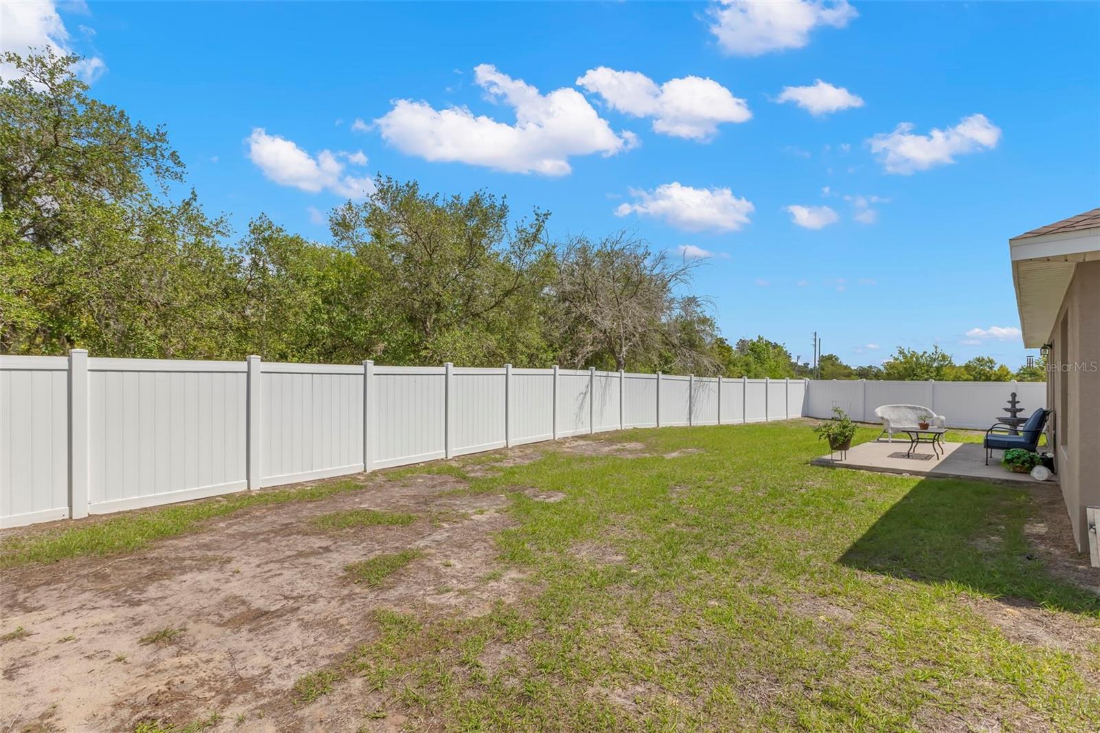 The expansive fenced backyard offers abundant green space for pets, play, gardening, or future outdoor enhancements, with a private patio already in place for relaxing or entertaining.