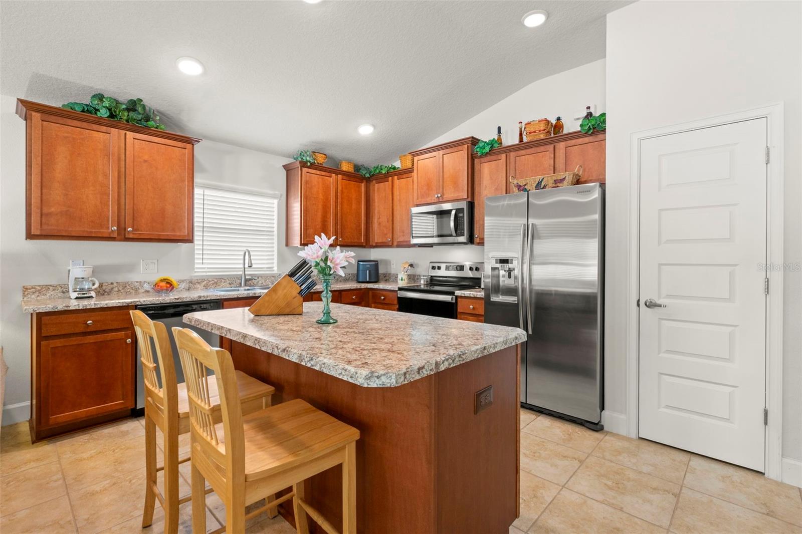 An oversized center island anchors the kitchen, offering additional prep space, breakfast bar seating, and a natural gathering point within the heart of the home.