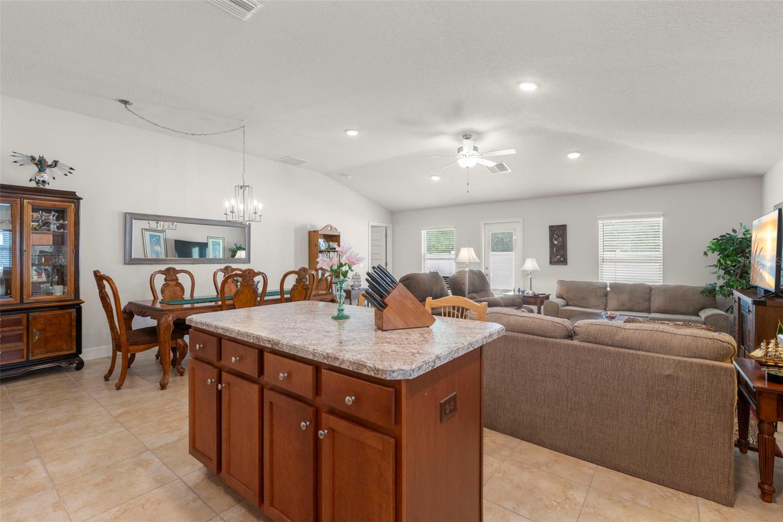 From the kitchen island, the home’s open-concept design and vaulted ceilings are on full display, creating an expansive central living space with seamless flow between kitchen, dining, and living areas.