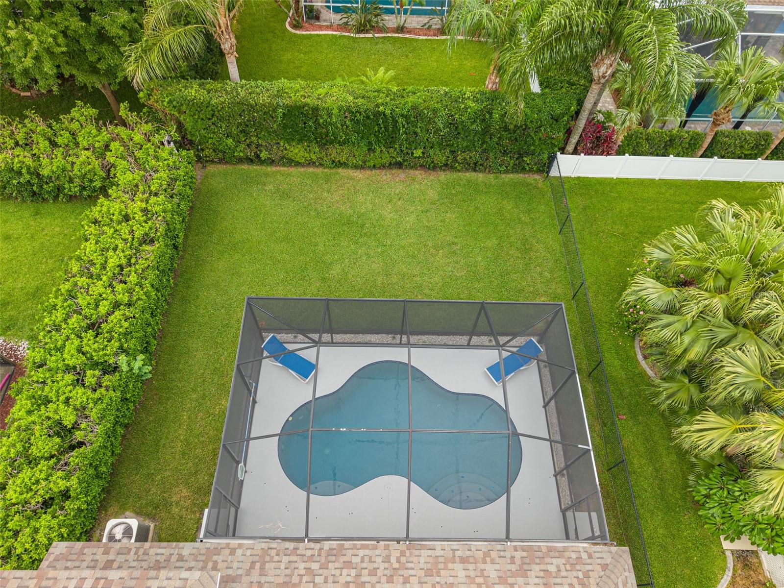 Aerial view of fenced yard with lush landscaping