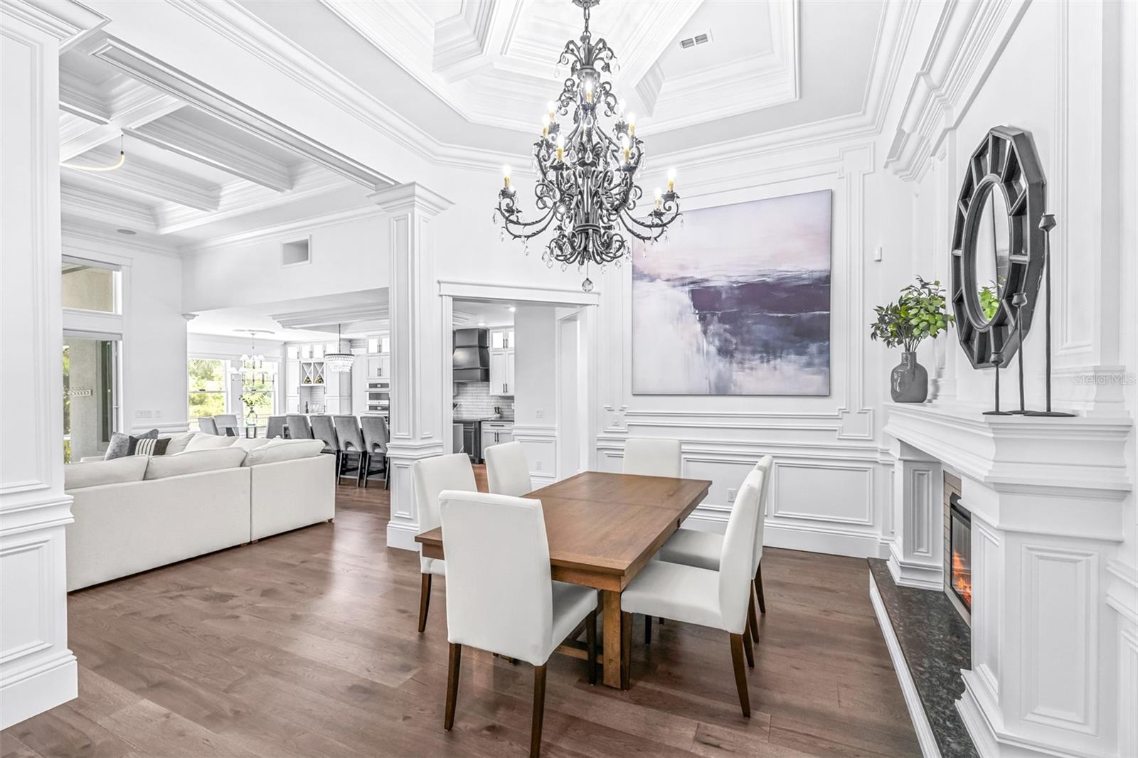 Formal Dining Room is Accented with an Enormous Custom Chandelier, Immaculately Trimmed Columns, an Electric Fireplace with Multiple Settings surrounded by a Tailor-Made Mantle