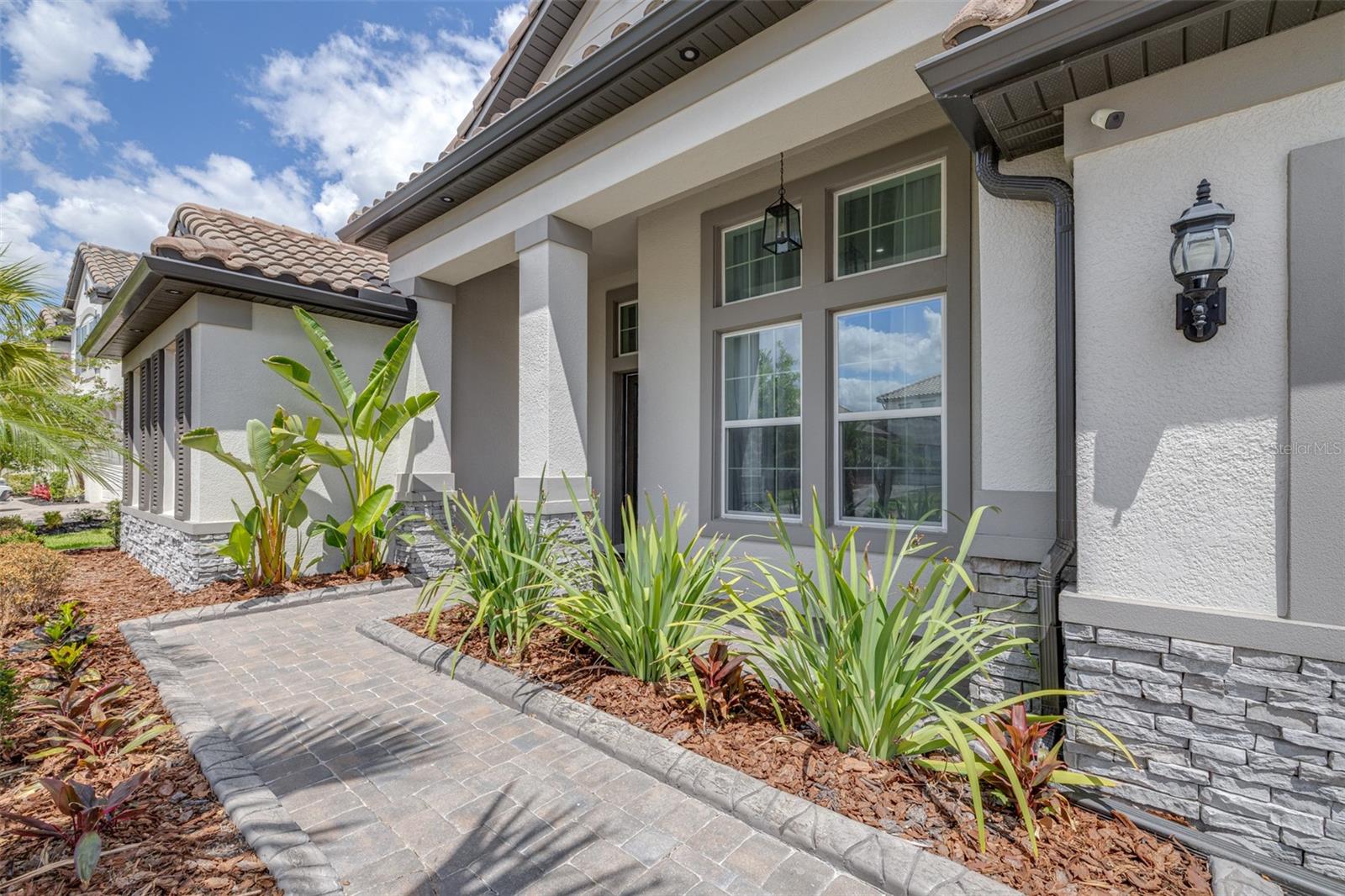 A Welcoming Front Porch overlooks Beautifully-lit Landscaping and the Neighborhood Park