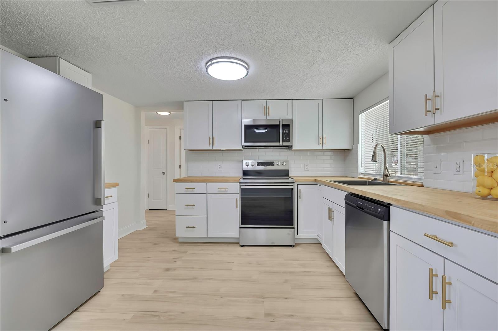 KITCHEN WITH GOLD HARDWARE AND LUXURY VINYL PLANK FLOORS.