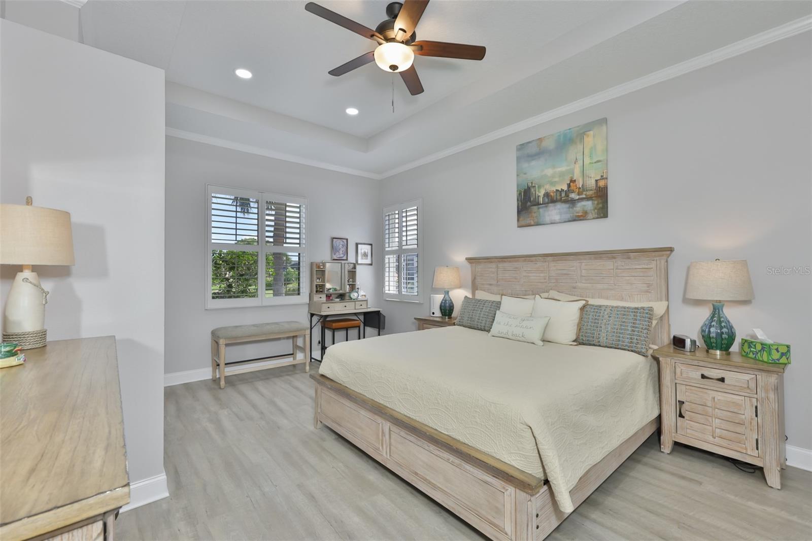 Primary bedroom is spacious with complimentary luxury vinyl flooring, crown molding and trey ceiling.