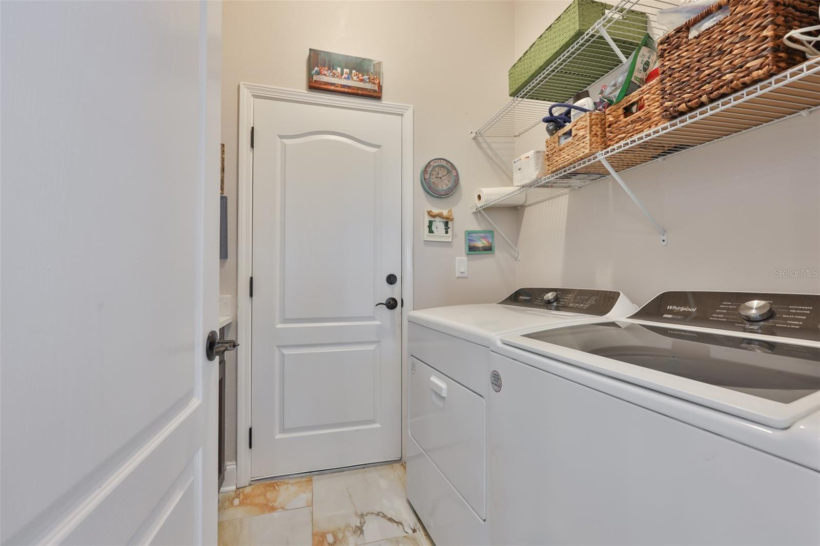 The laundry room offers shelving and counters for folding.