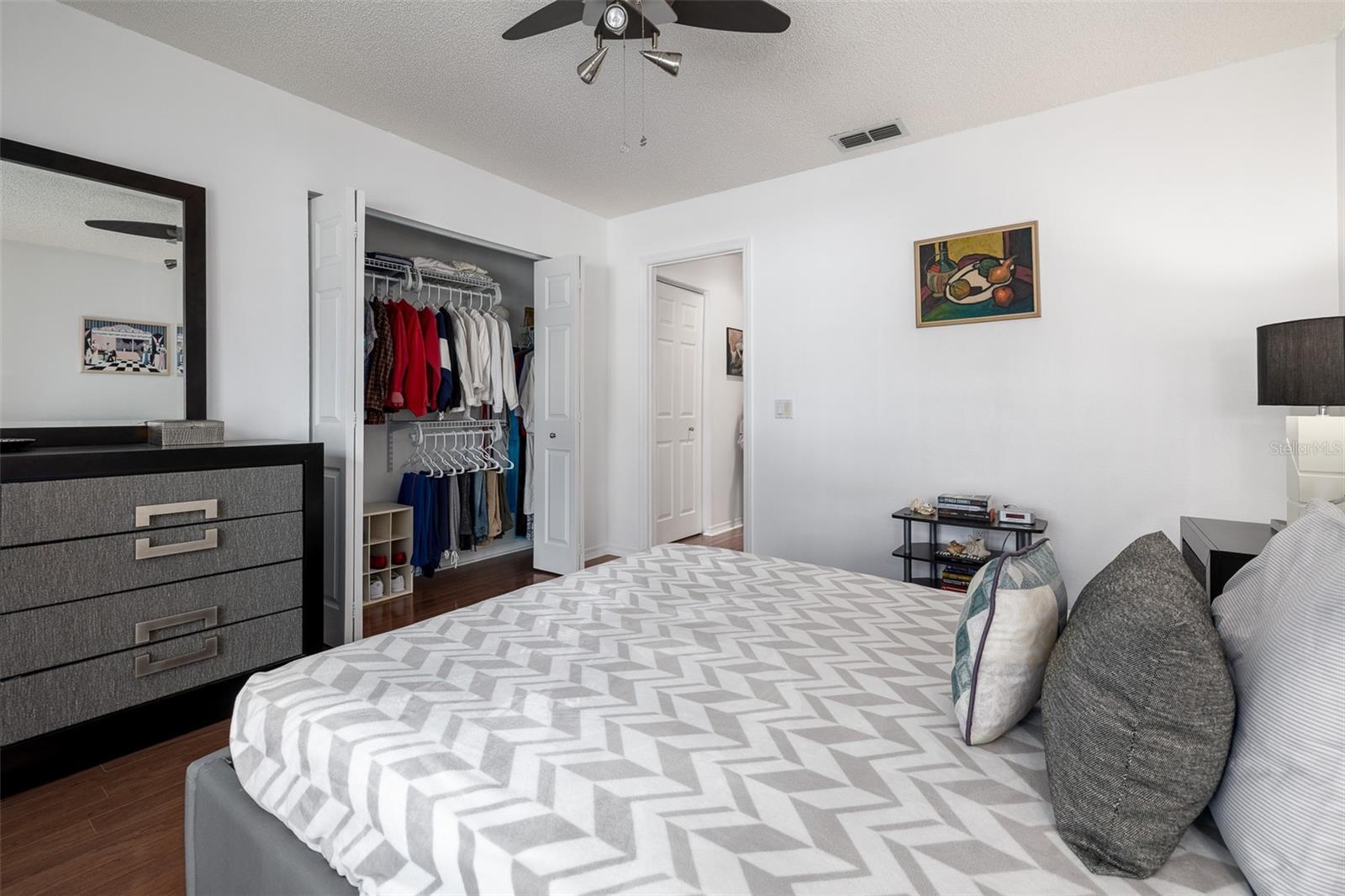 Owner's bedroom, ceiling fan, wood flooring, closet organized by custom shelving