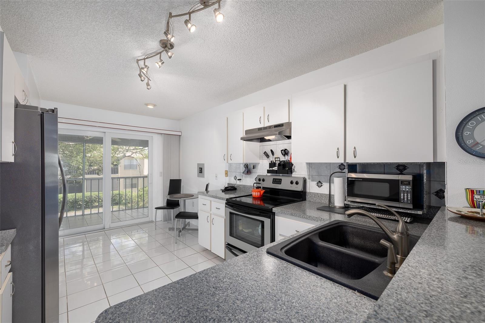 Kitchen with tile flooring, Eat-in Dining Space, sliding doors onto the large screened-in patio, with ceiling fan and tile flooring.
