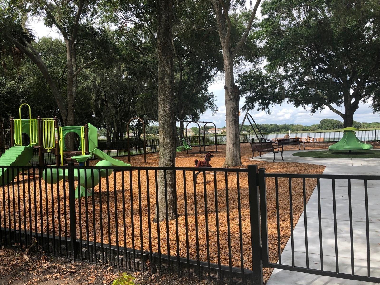 Lakefront playground enclosed by wrought iron fencing
