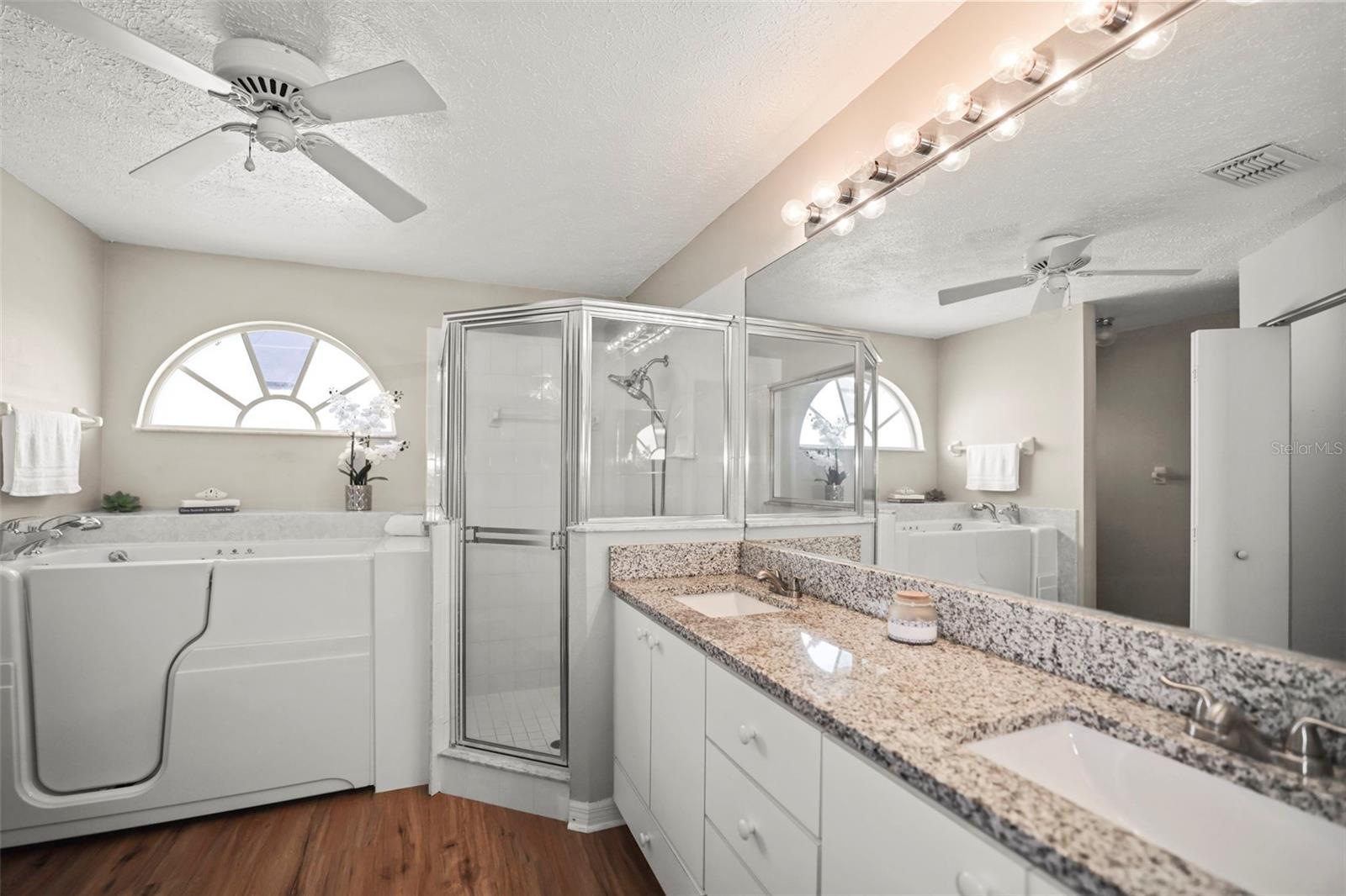 En-suite bath with double sink vanity, separate shower, and soak tub