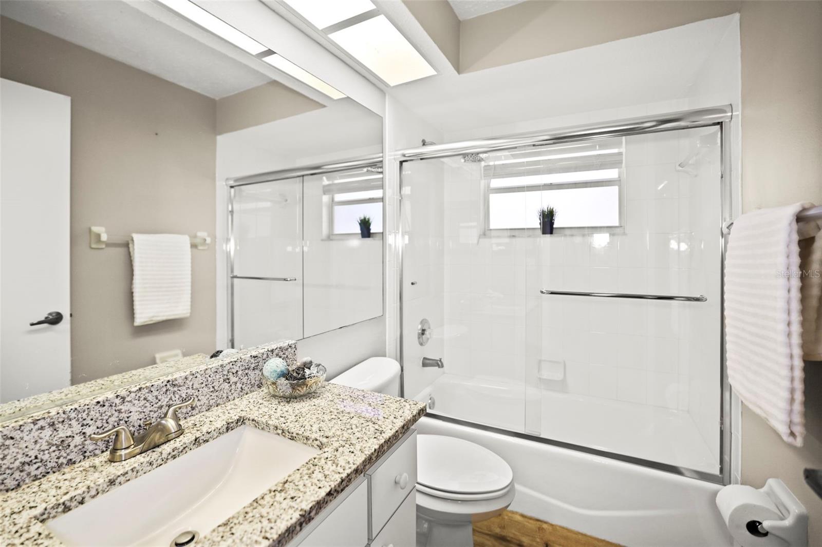 Guest Bath with bathtub, granite countertop and window allowing natural light.