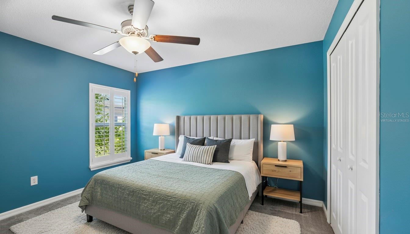 Bedroom Two - Virtually StagedSecond bedroom with carpet flooring, ceiling fan, plantation shutters, and a reach-in closet with bifold doors.