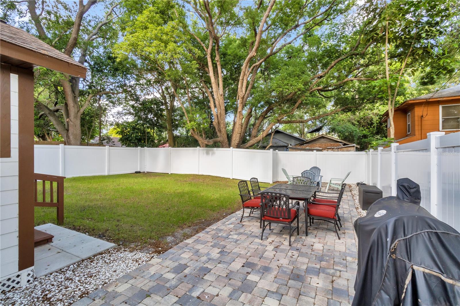 A generous backyard offers lush grassy areas and a paver patio—perfect for relaxing by the firepit and grilling.