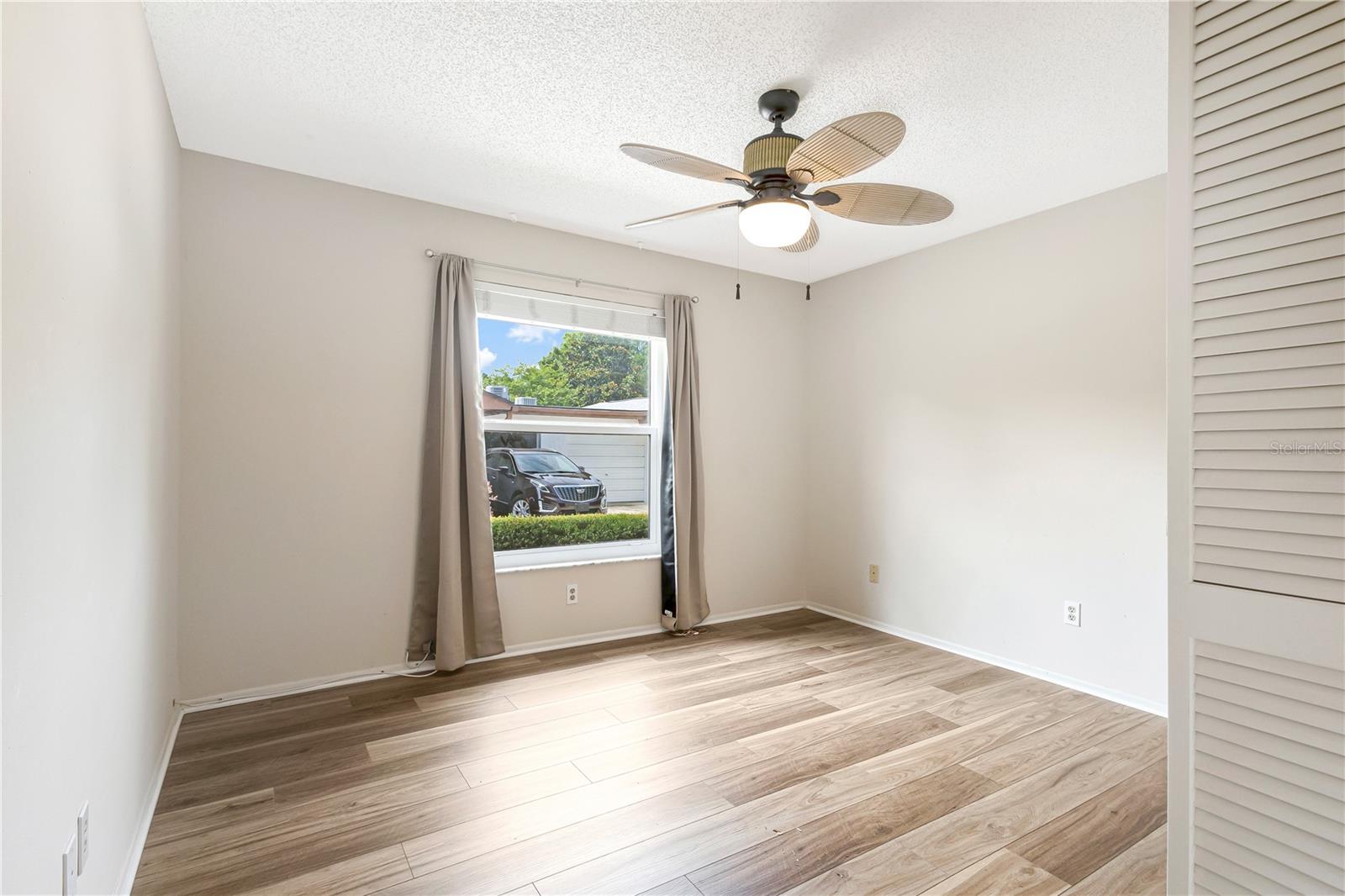 Guest bedroom with ceiling fan and large window that allows natural light