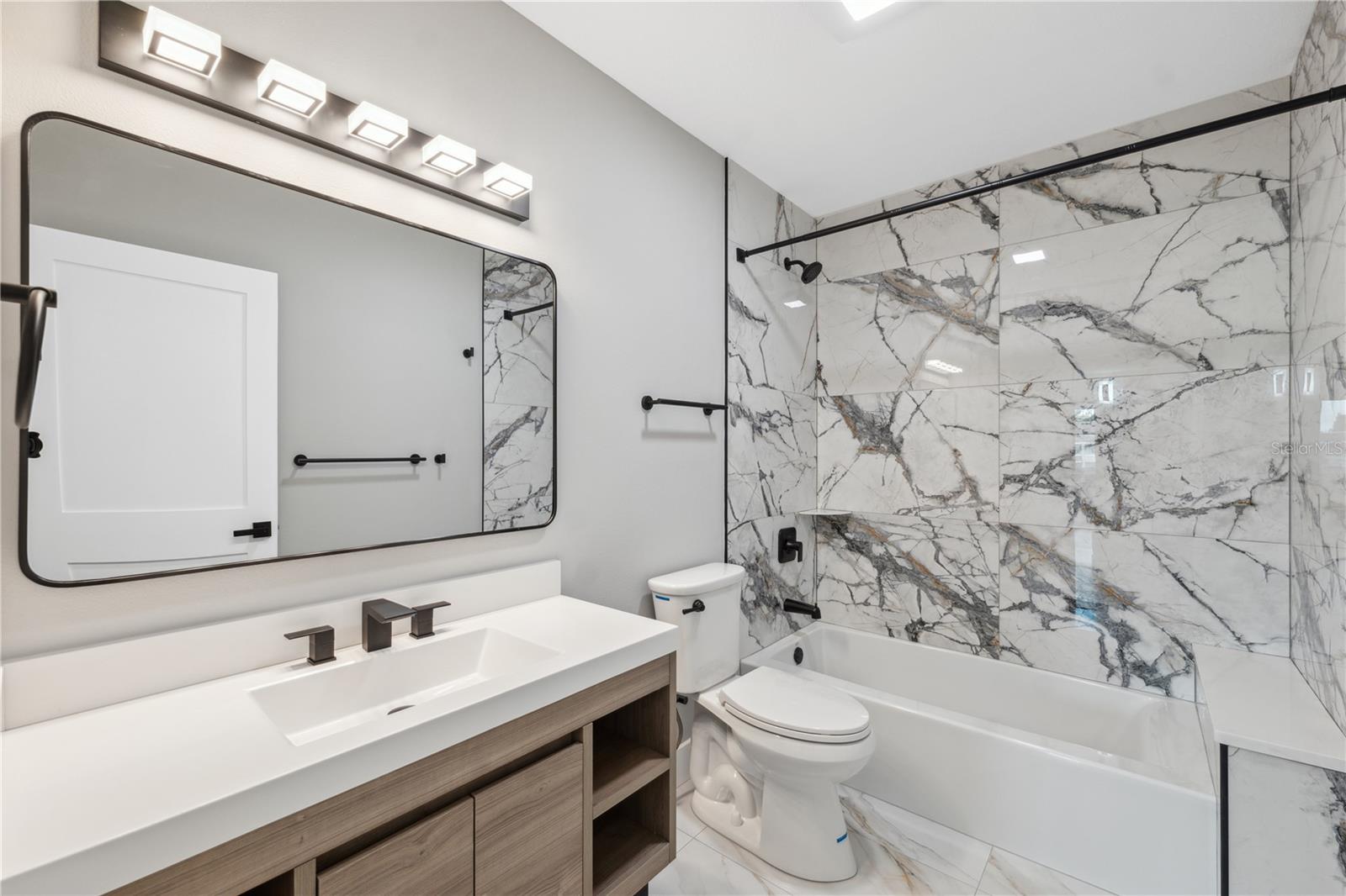 guest bathroom fully renovated with deep soaker tub , lighting , and ceramic tile