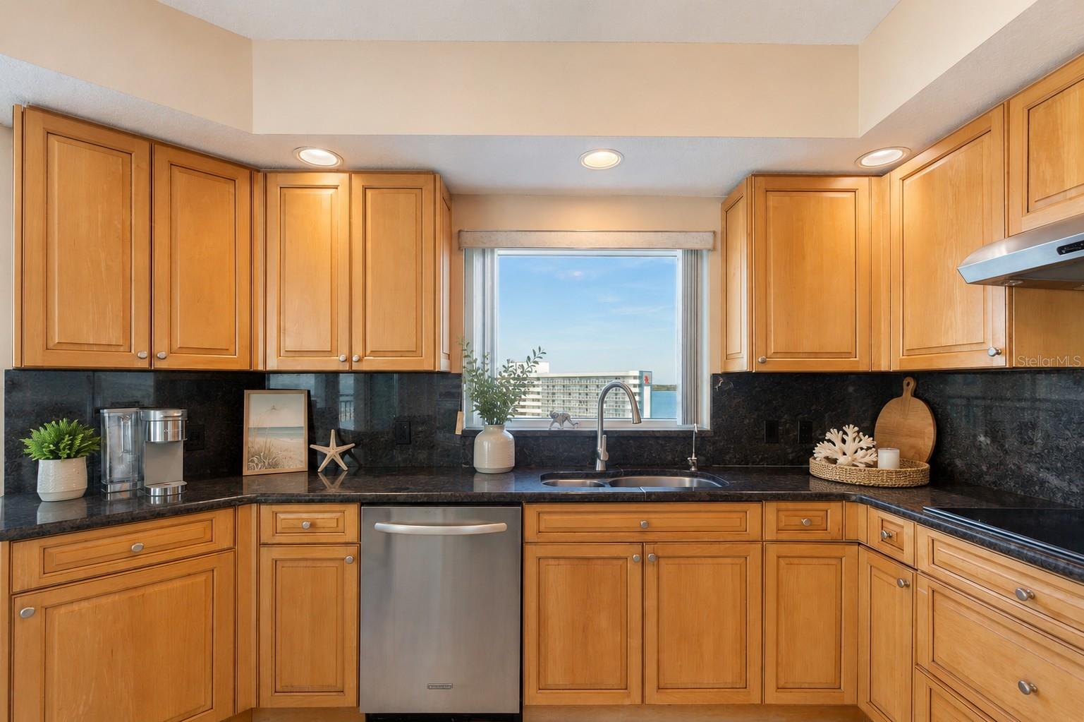 AI staged. Plenty of granite countertop space to make a meal for family and friends. You even have water views when doing the dishes!