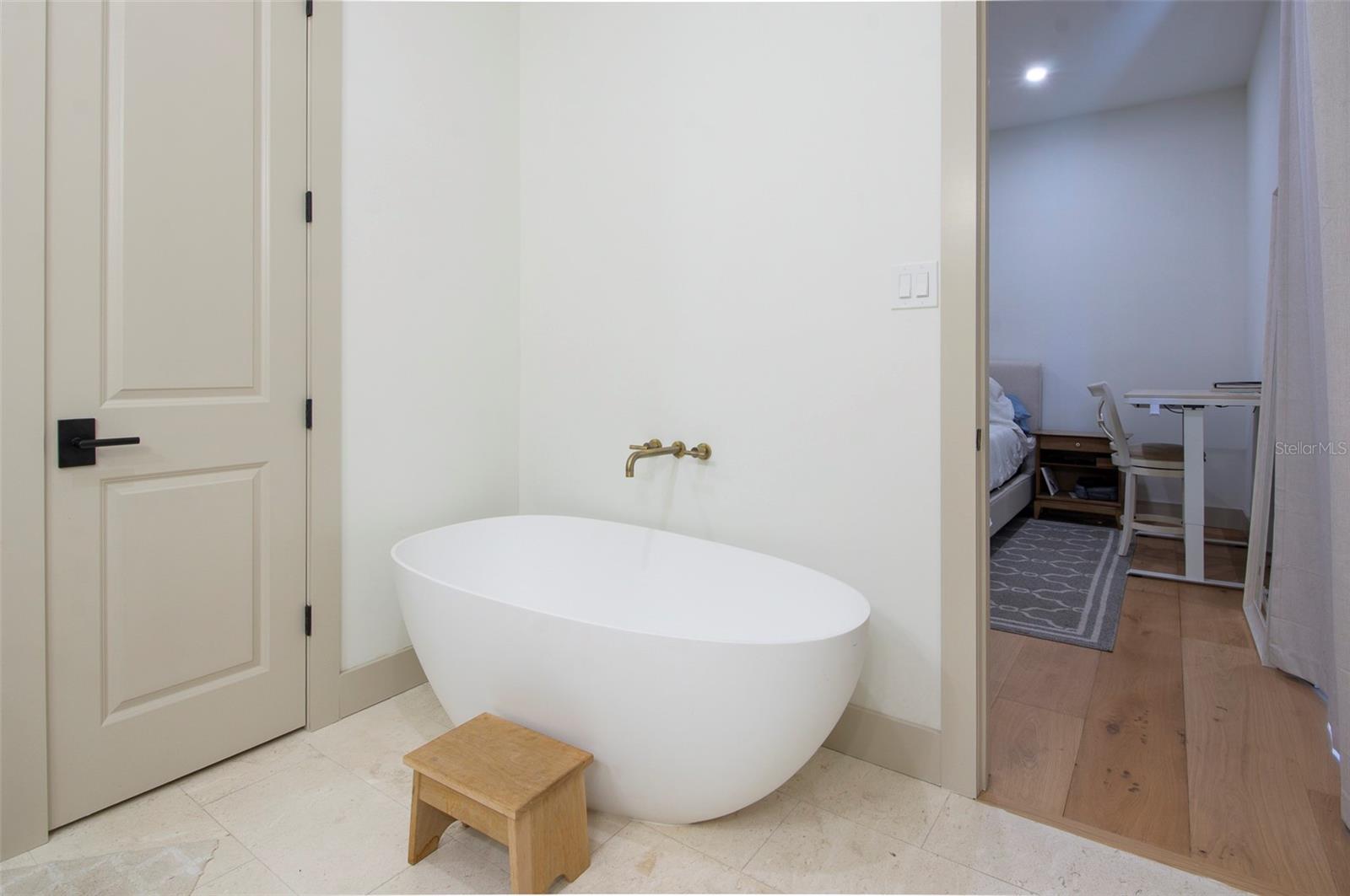 A spa-inspired bath featuring a freestanding tub, oversized shower, dual vanities, and white oak cabinetry