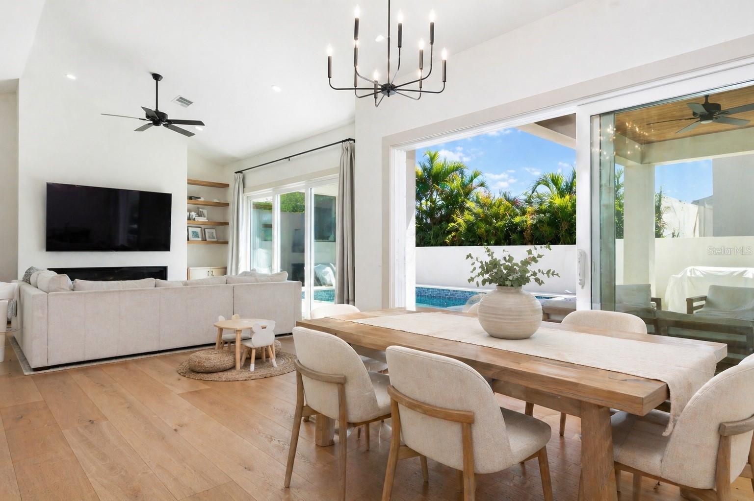 Digitally enhanced to show dining table. The living room transitions seamlessly to the outdoor space through two expansive hurricane impact 12-foot sliding glass doors that fully open, creating true indoor-outdoor living ideal for both entertaining and everyday flow.