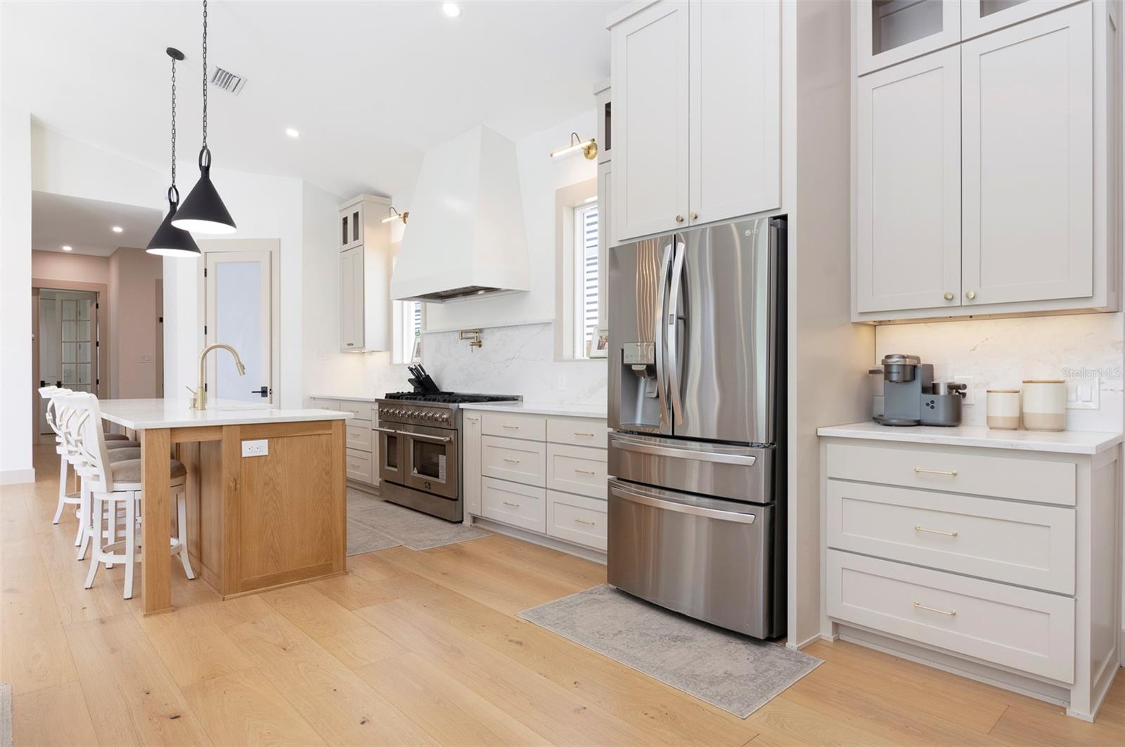 The chef’s kitchen features an 8-burner gas range, oversized island, custom-built pantry, custom built cabinetry with soft close hinges, and premium appliances