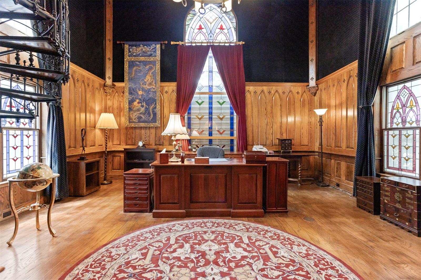 Majestic Office at South end of the home boasts soaring ceilings and exquisite stained glass windows, wood floors and a spiral staircase up to the second level